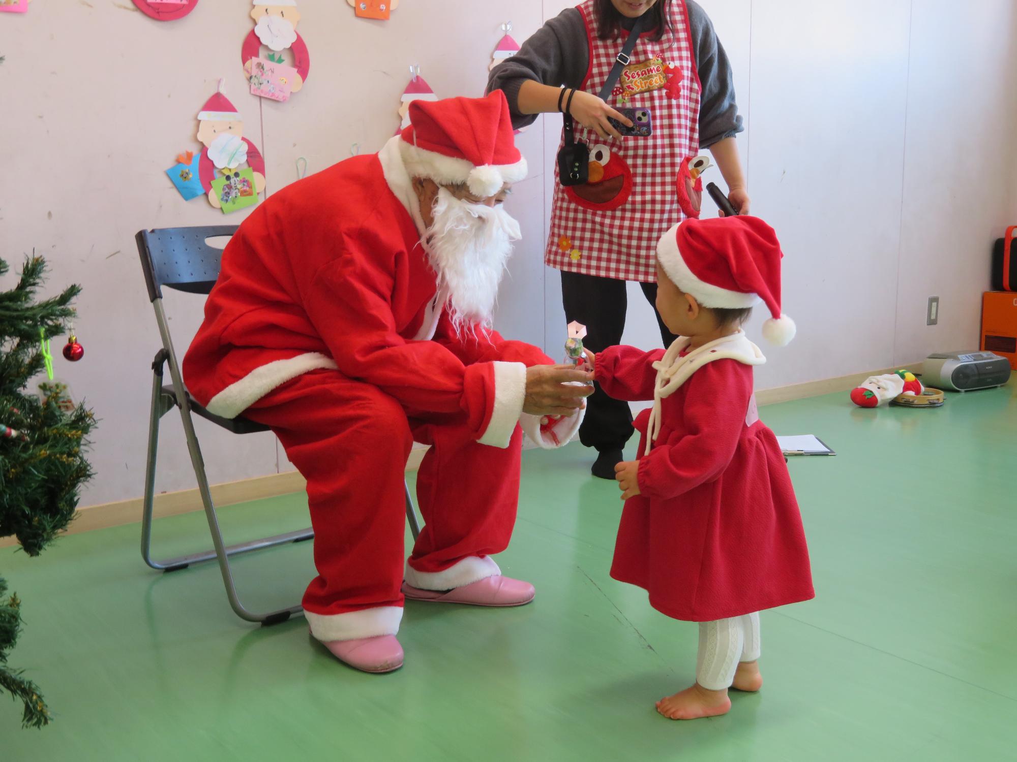 サンタに扮した地域ボランティアの方からプレゼントをもらう参加幼児の写真