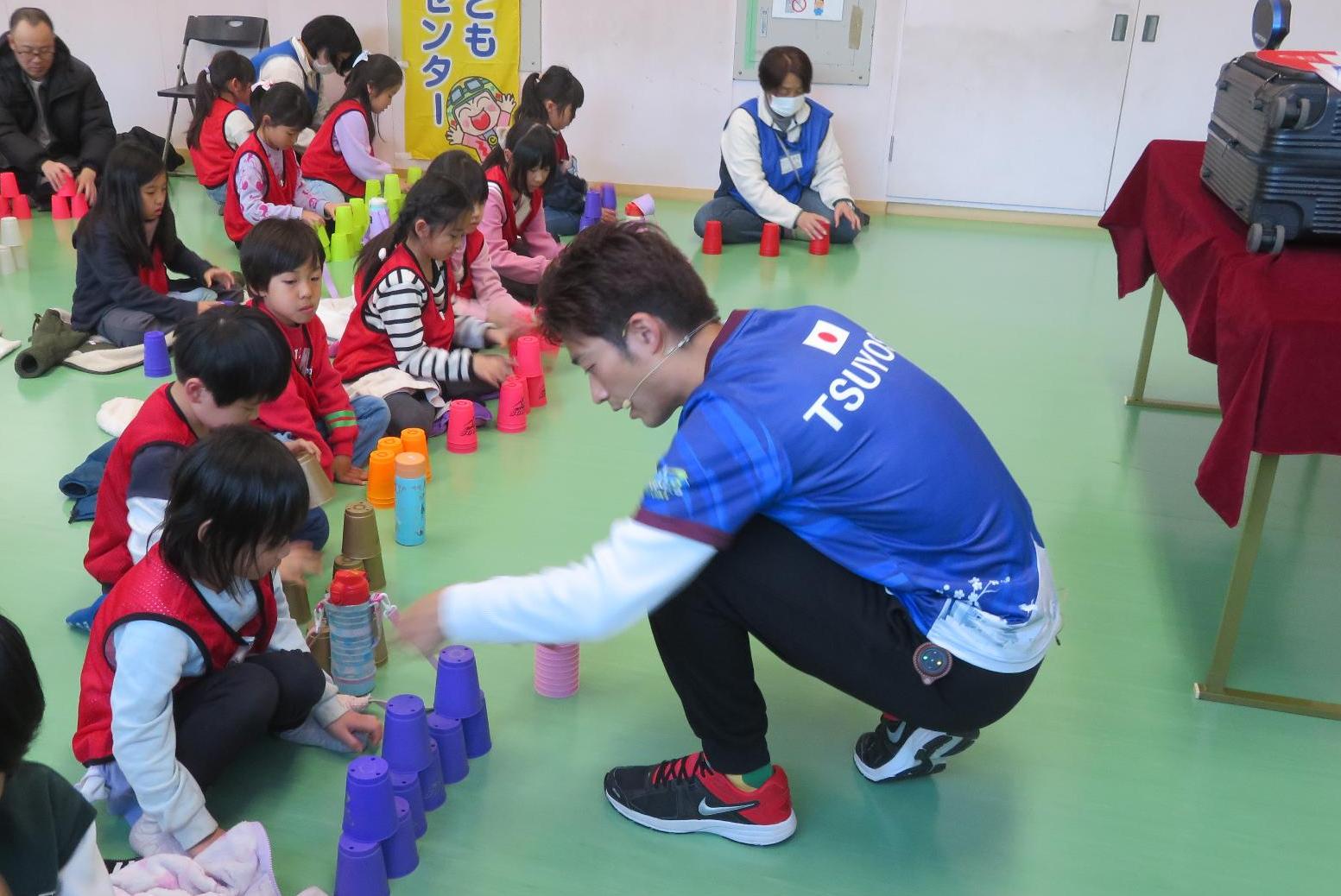講師にスポーツスタッキングを教わる小学生児童の様子の写真