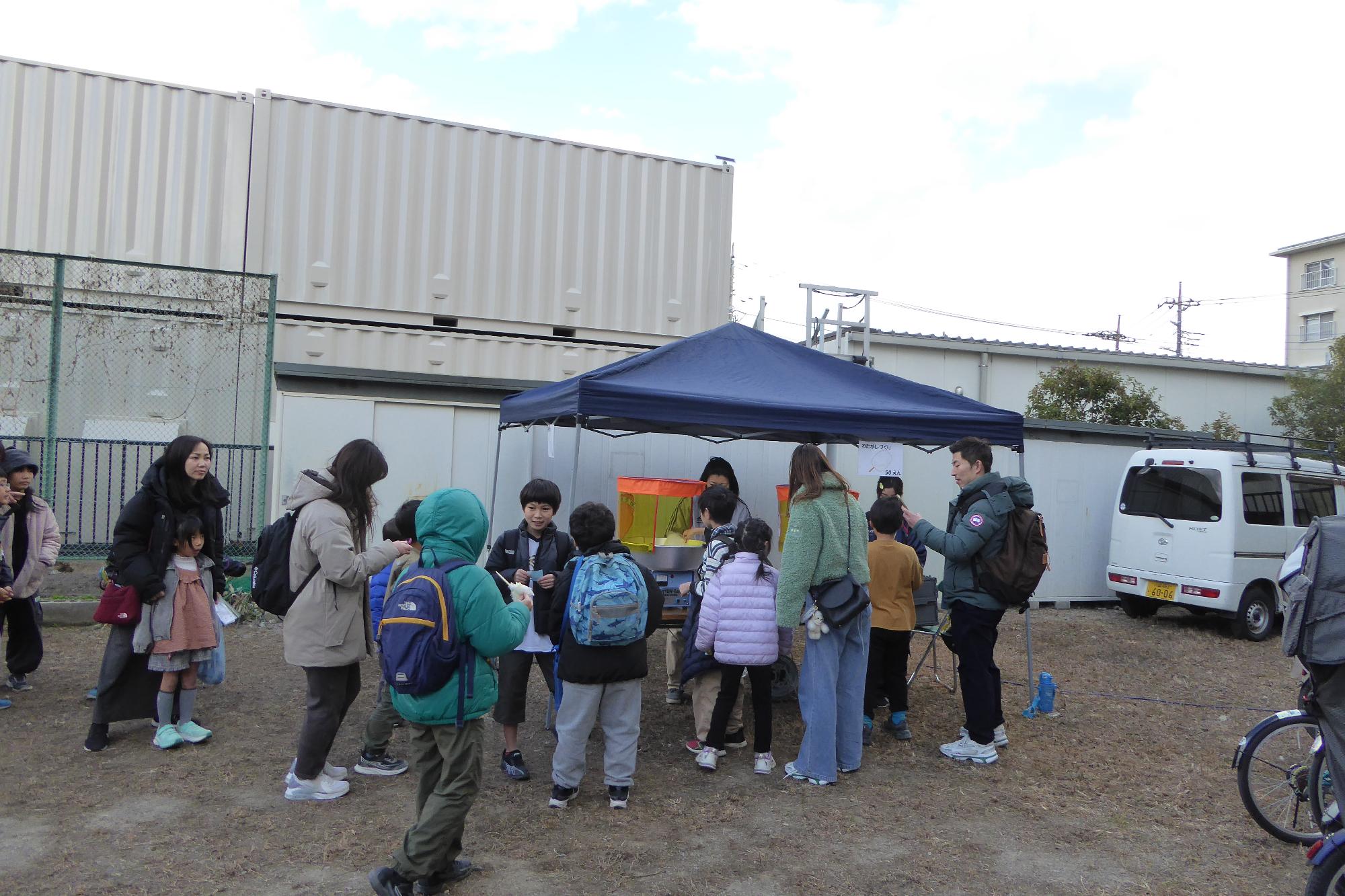 わたがし作りの体験コーナーに並ぶ参加者の様子の写真