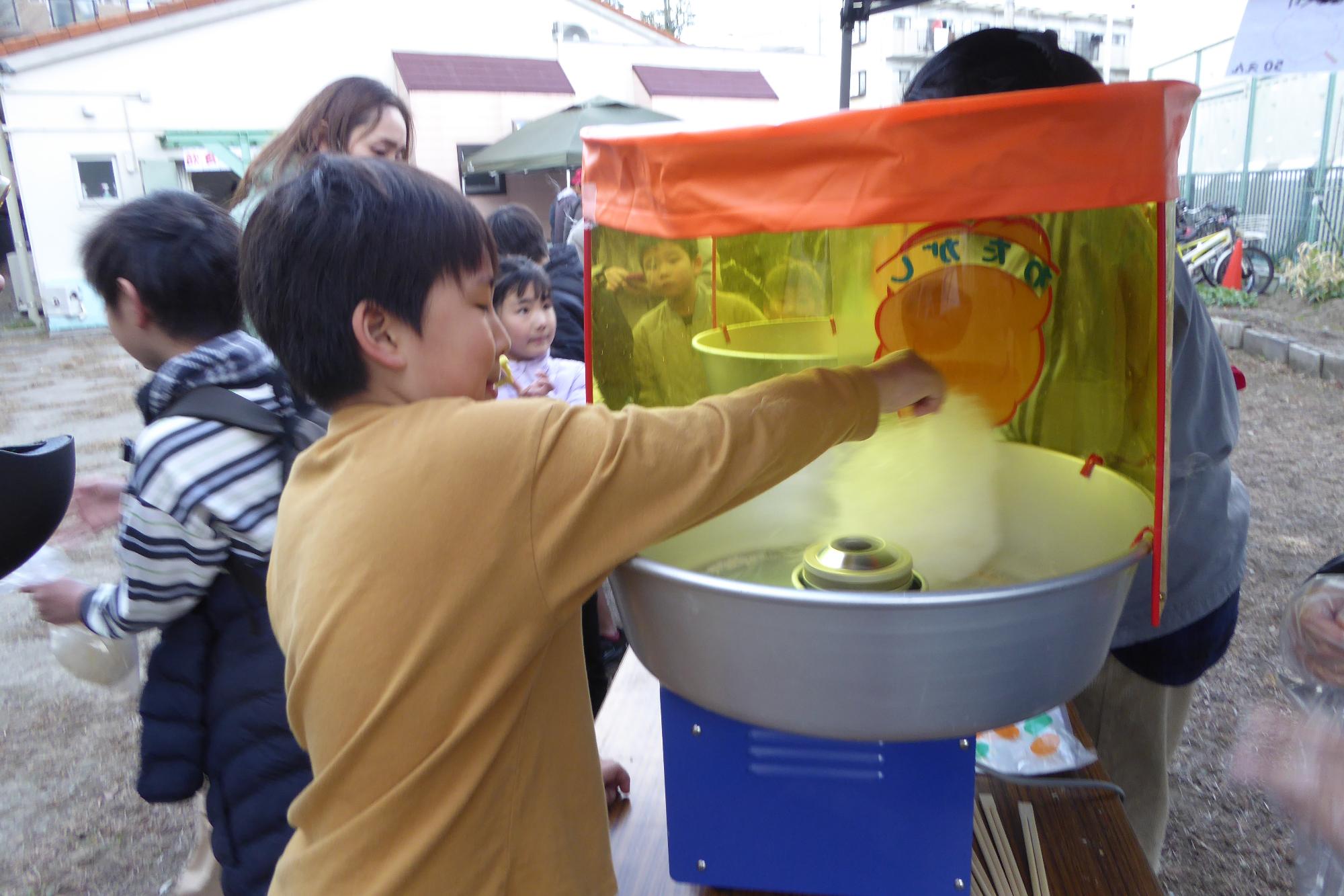 小学生児童が上手にわたがしを作っている様子の写真