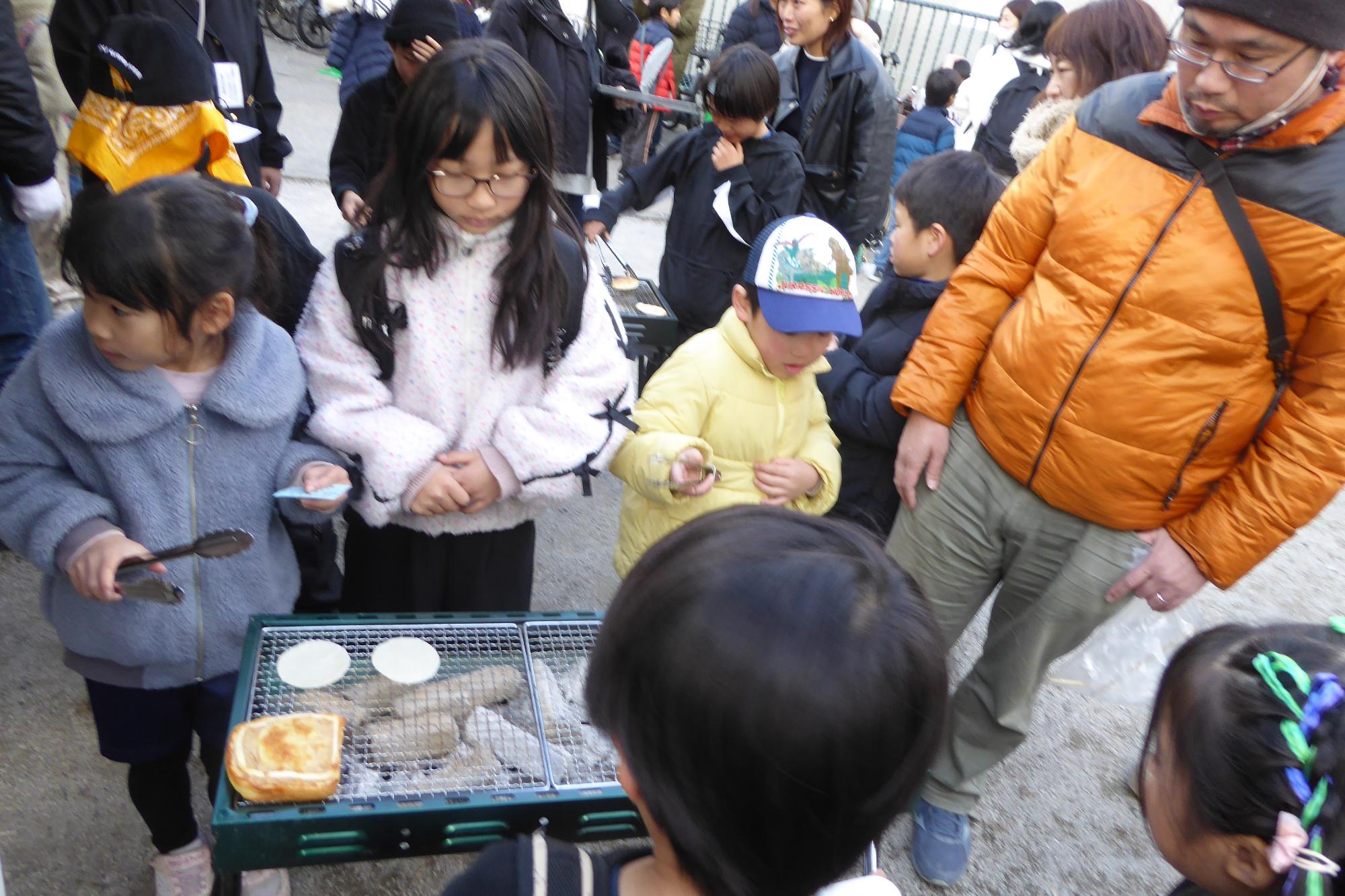 おせんべいやきに挑戦する小学生児童の様子の写真
