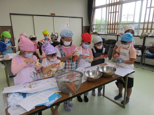 中学年グループがピーラーで野菜の皮むきをしている写真