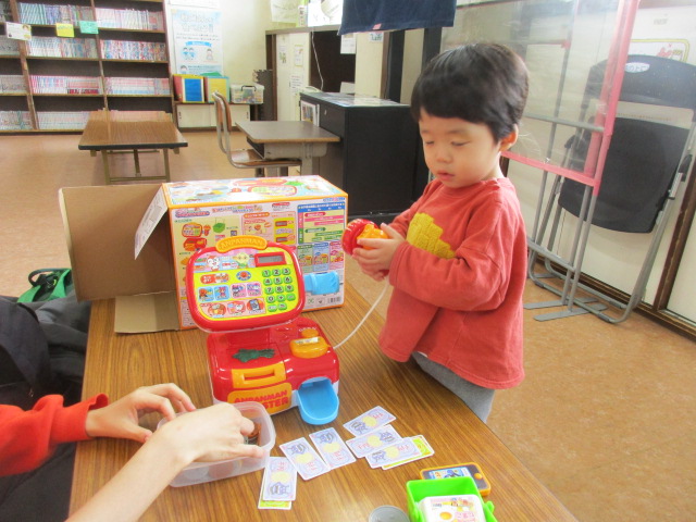 新しいおもちゃレジスターで遊んでいる幼児の写真