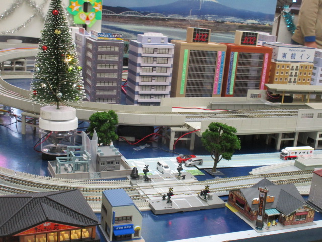 沢山のビルが並んでいる周囲にレールが設置され、鉄道が走っている大きな模型の写真