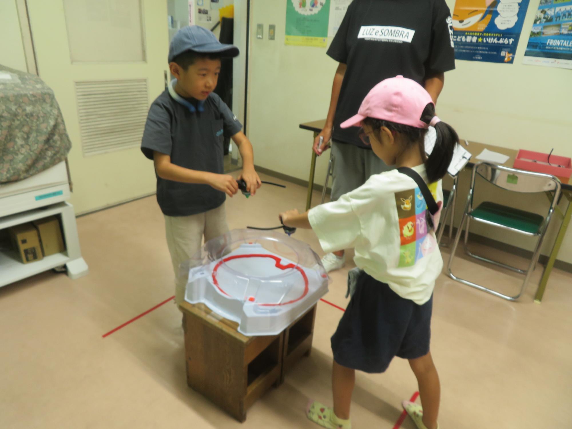 男の子と女の子がベイブレードをしている写真