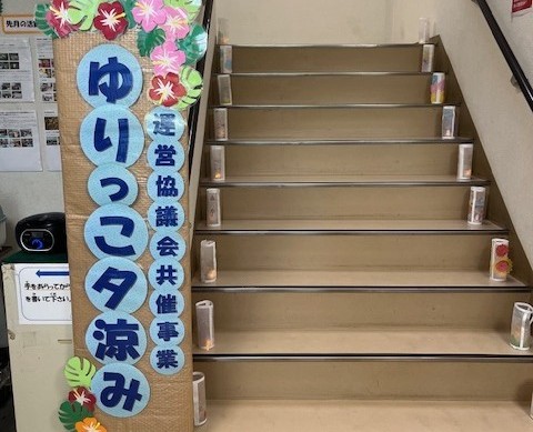 階段に飾ってあるランタンと、ゆりっこ夕涼みの立て看板の写真