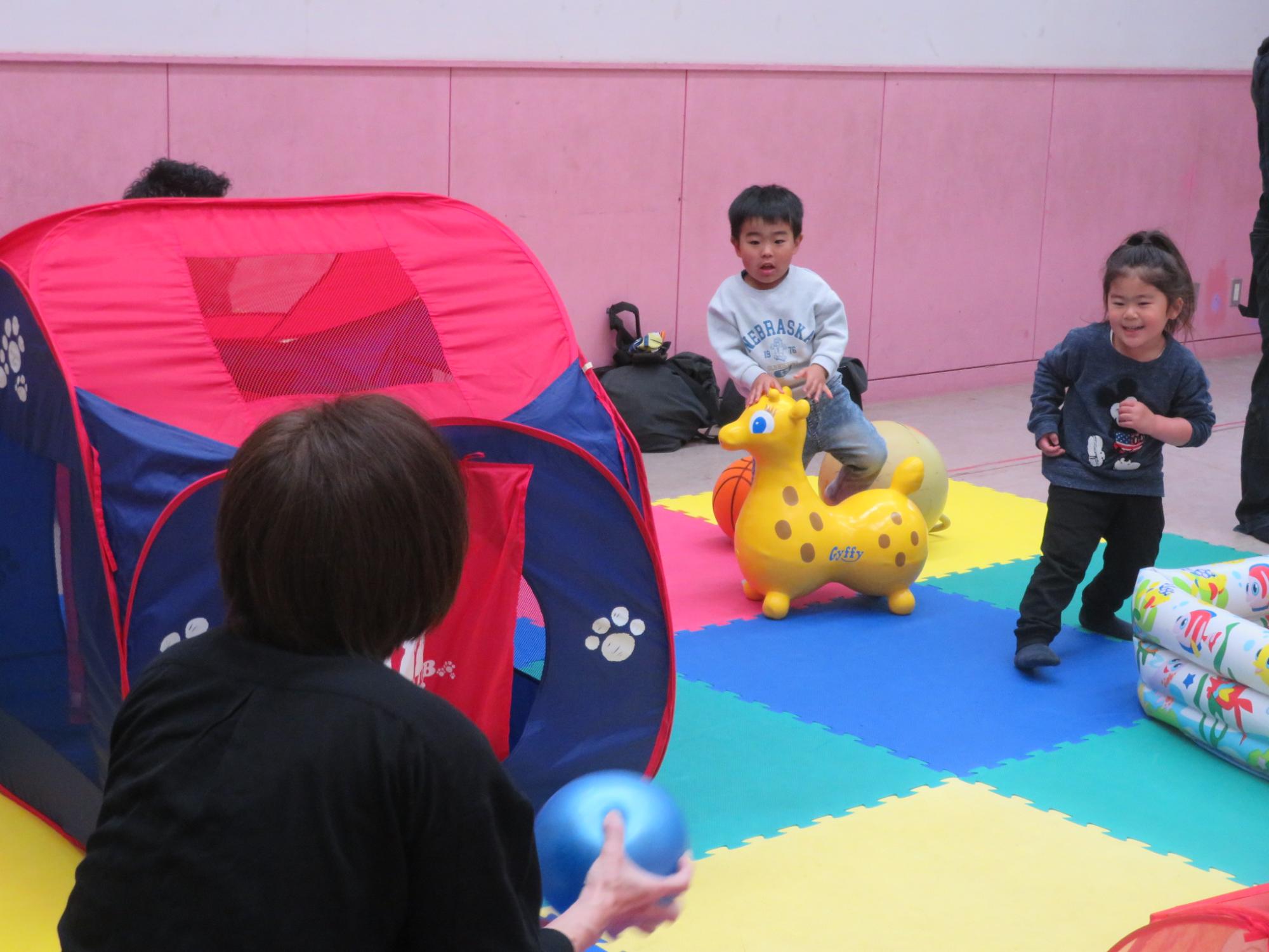 幼児とスタッフががボールで遊んでいる写真
