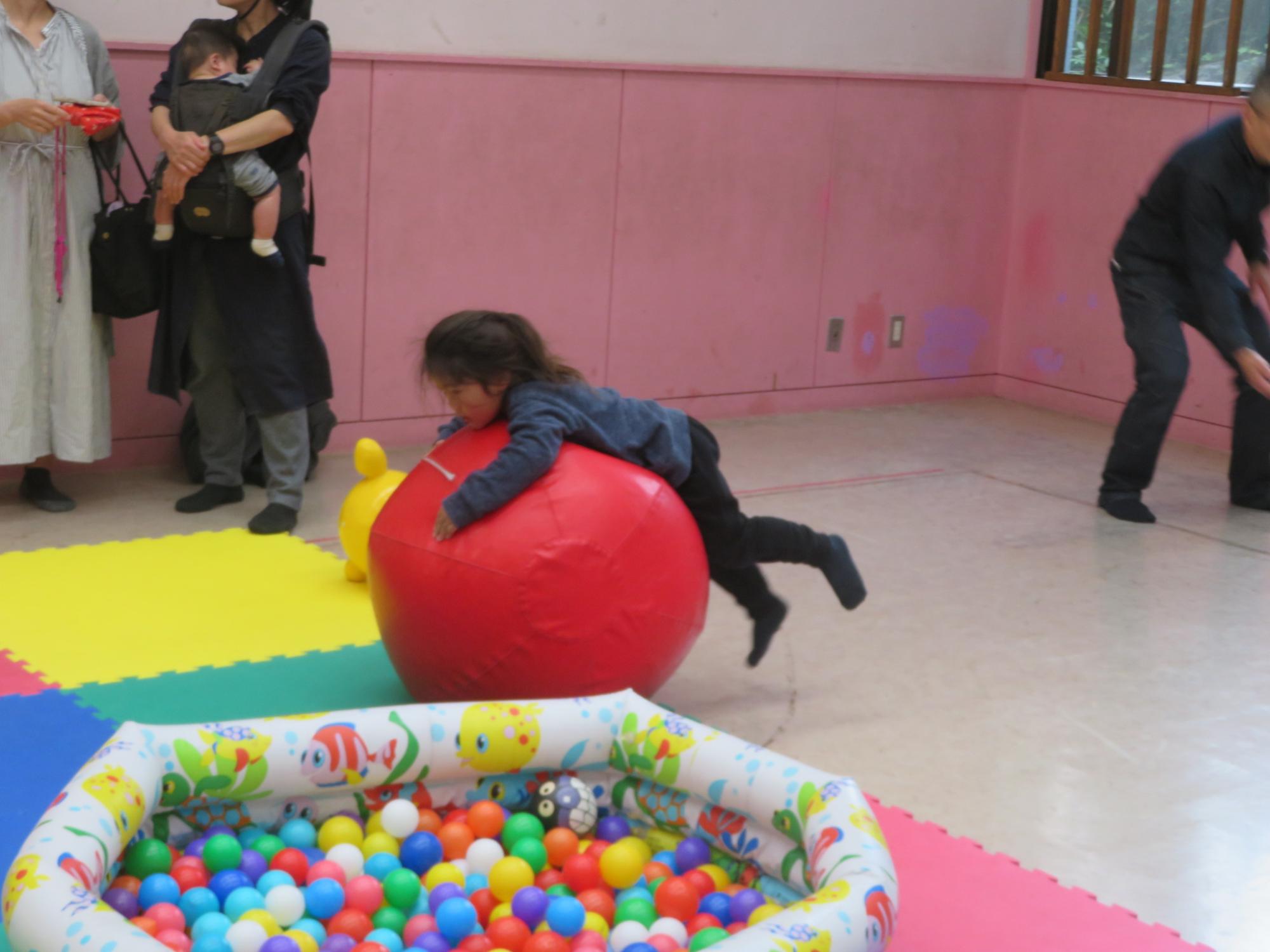 幼児が赤い大玉に乗っている写真