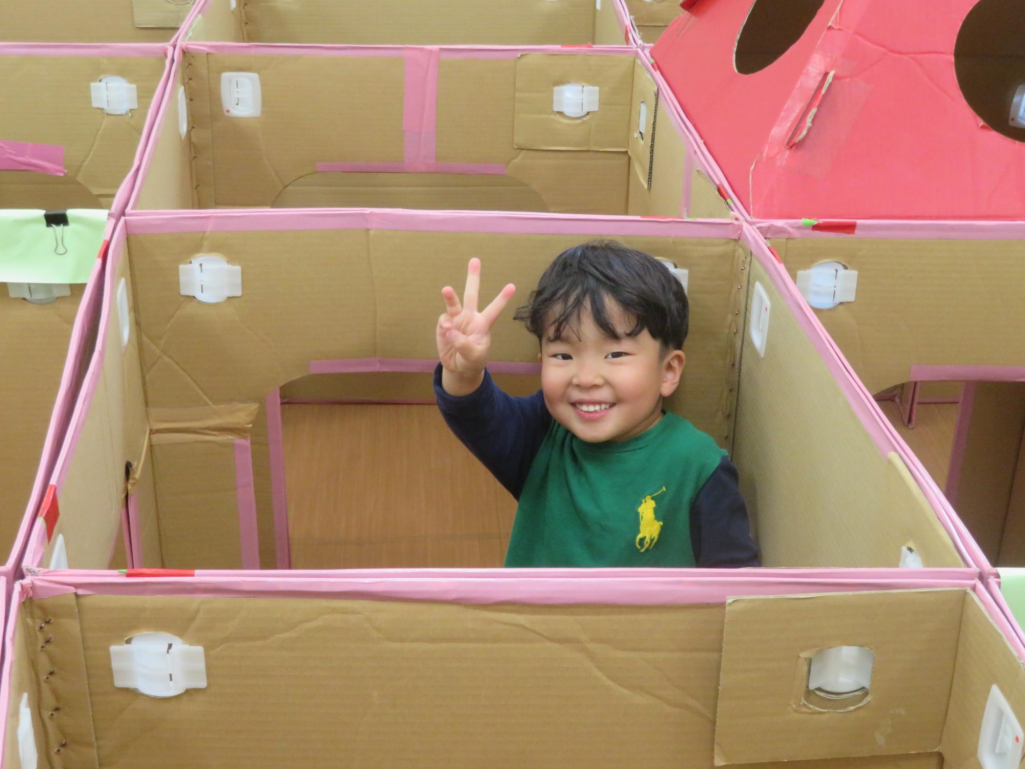 ダンボール迷路内でポーズをとっている男の子の様子