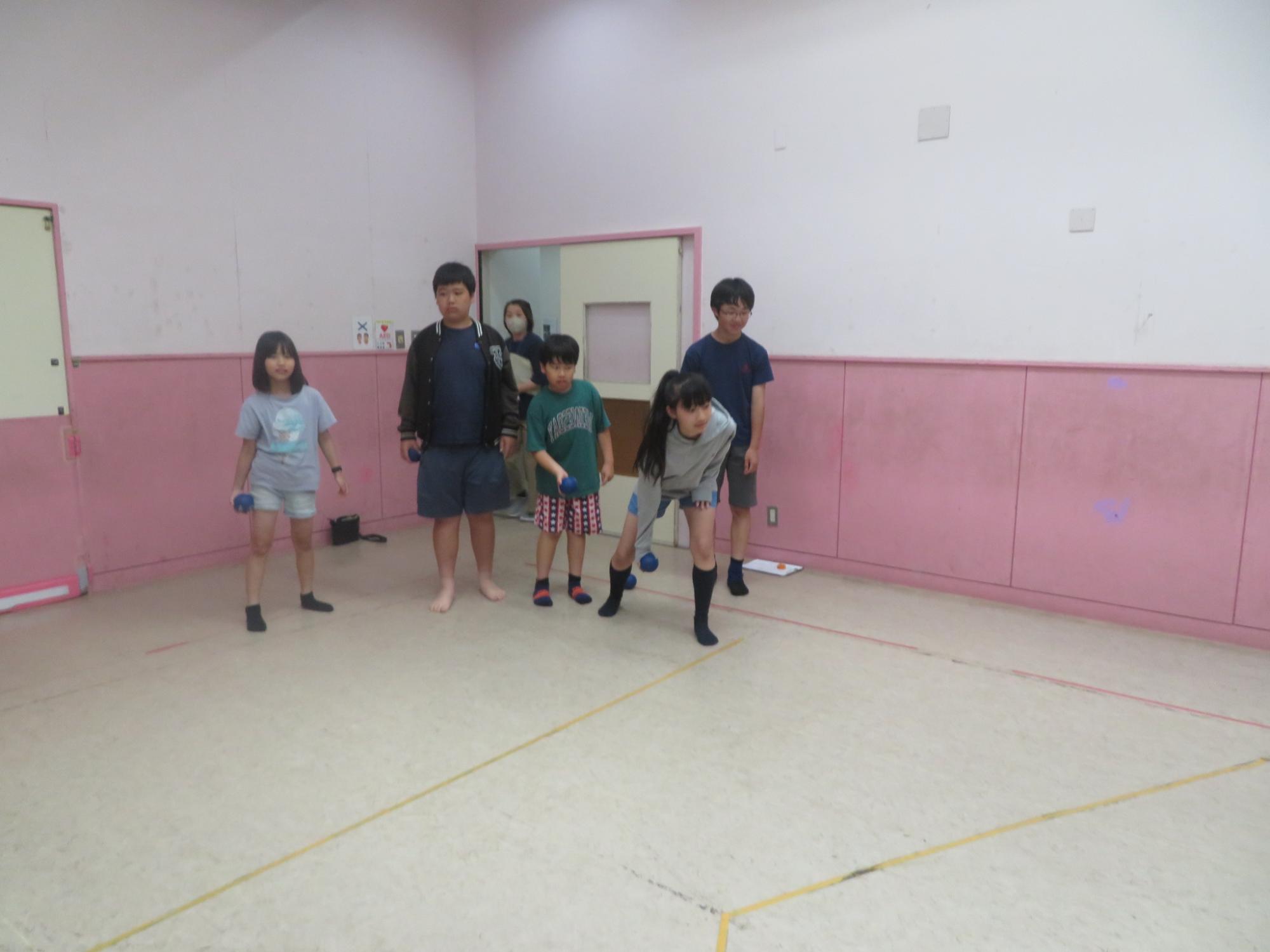 ボッチャのボールを投げ終わるこどもとそれを見守る子ど達の様子