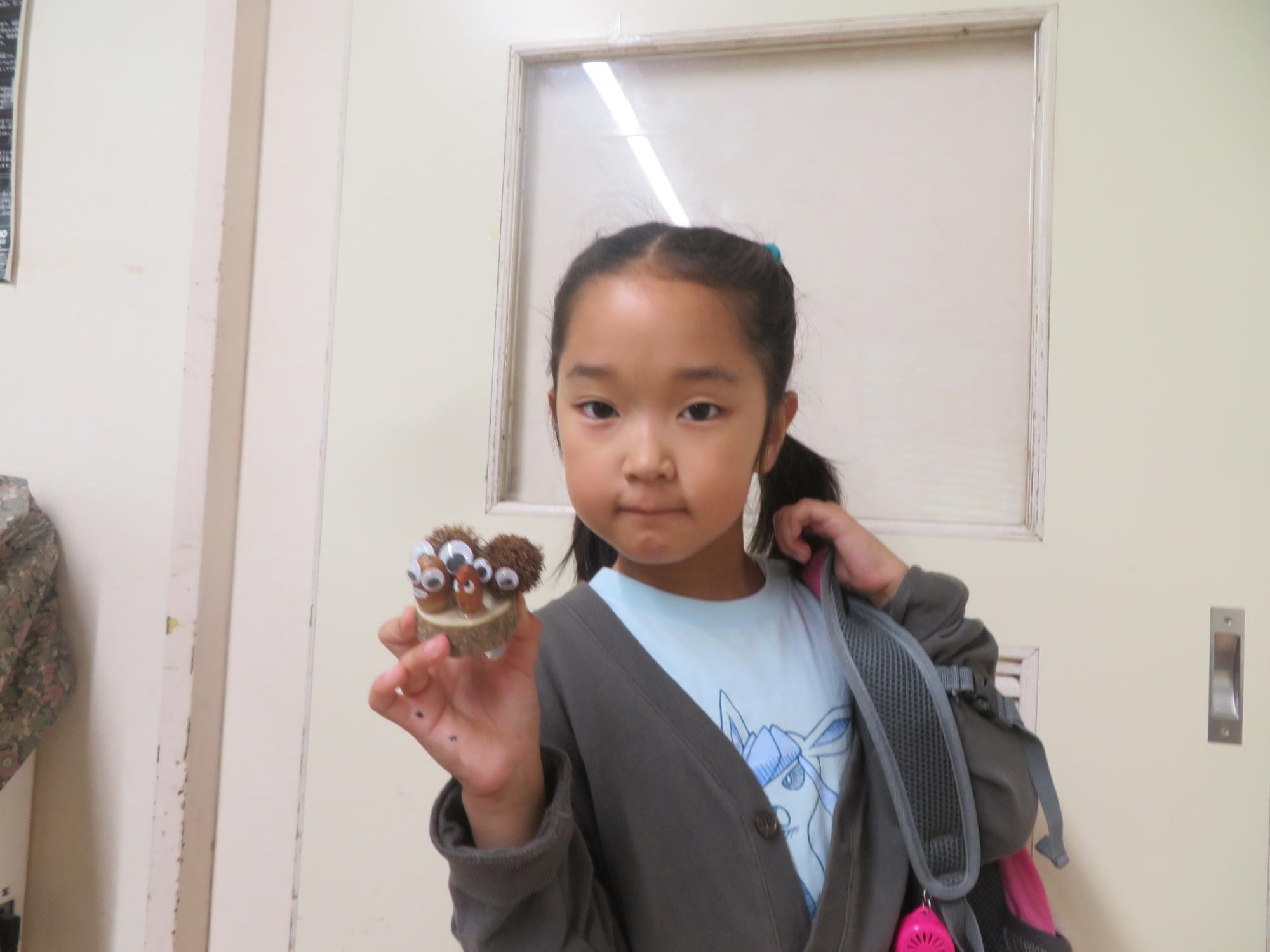 完成したどんぐり工作を持ってポーズしている小学生の女の子の様子