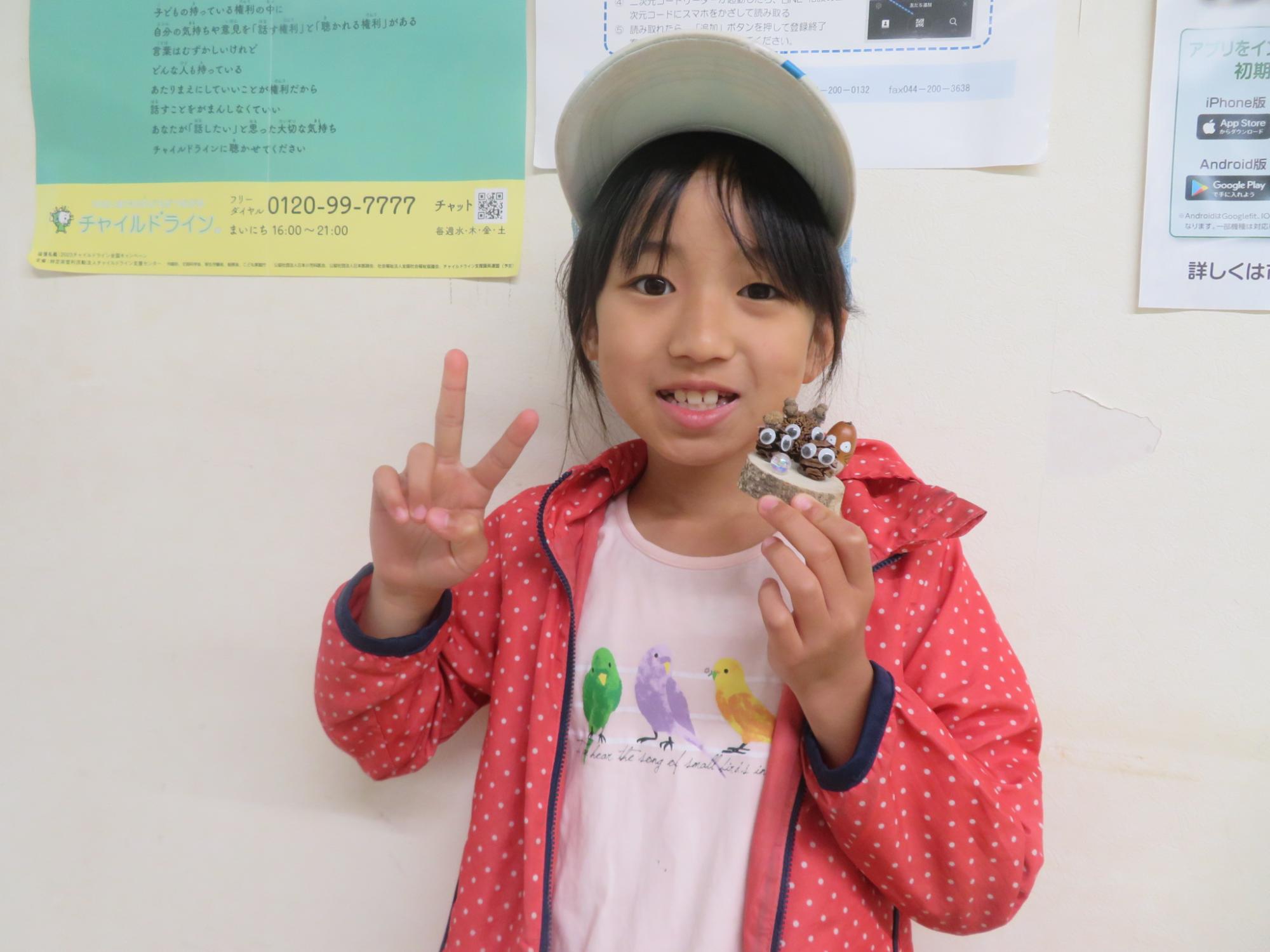 完成したどんぐり工作を持ってポーズしている小学生の女の子の様子