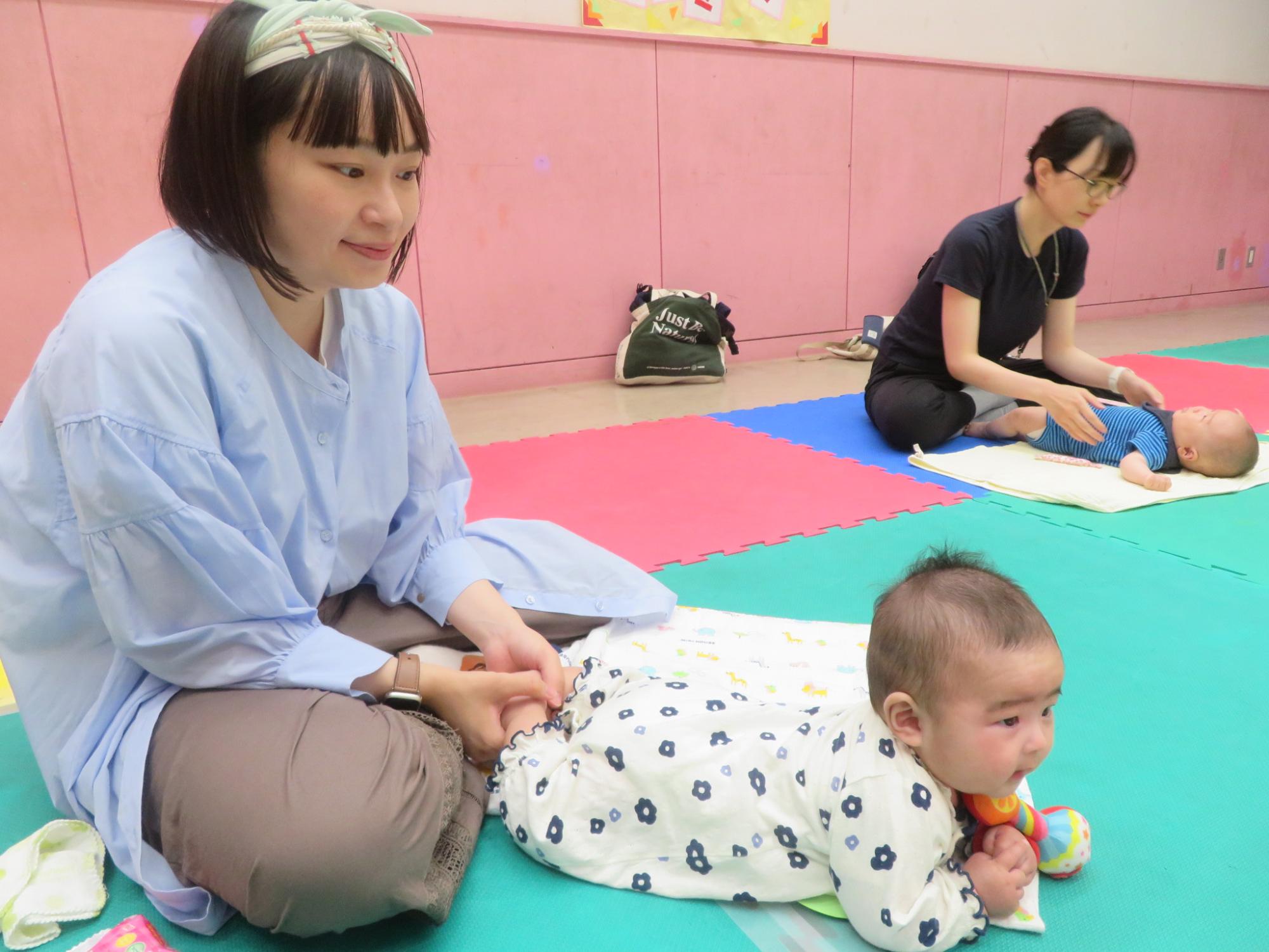 うつ伏せで顔を上げた赤ちゃんと保護者の様子
