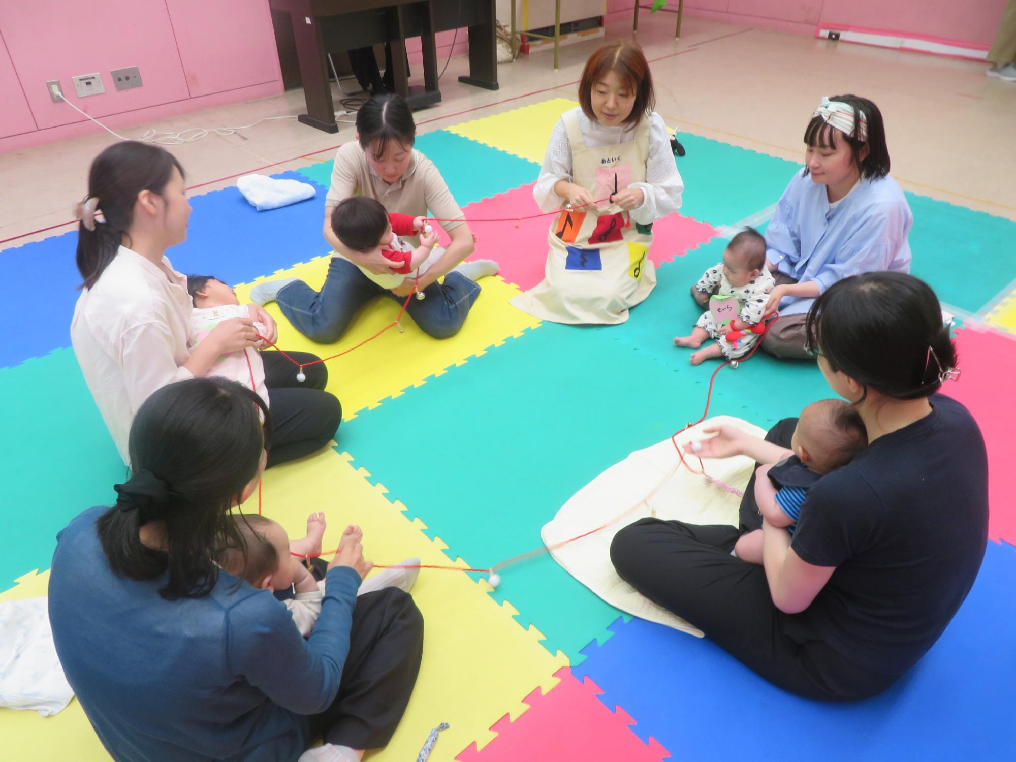 輪になって鈴のついたひもを持つ親子の様子