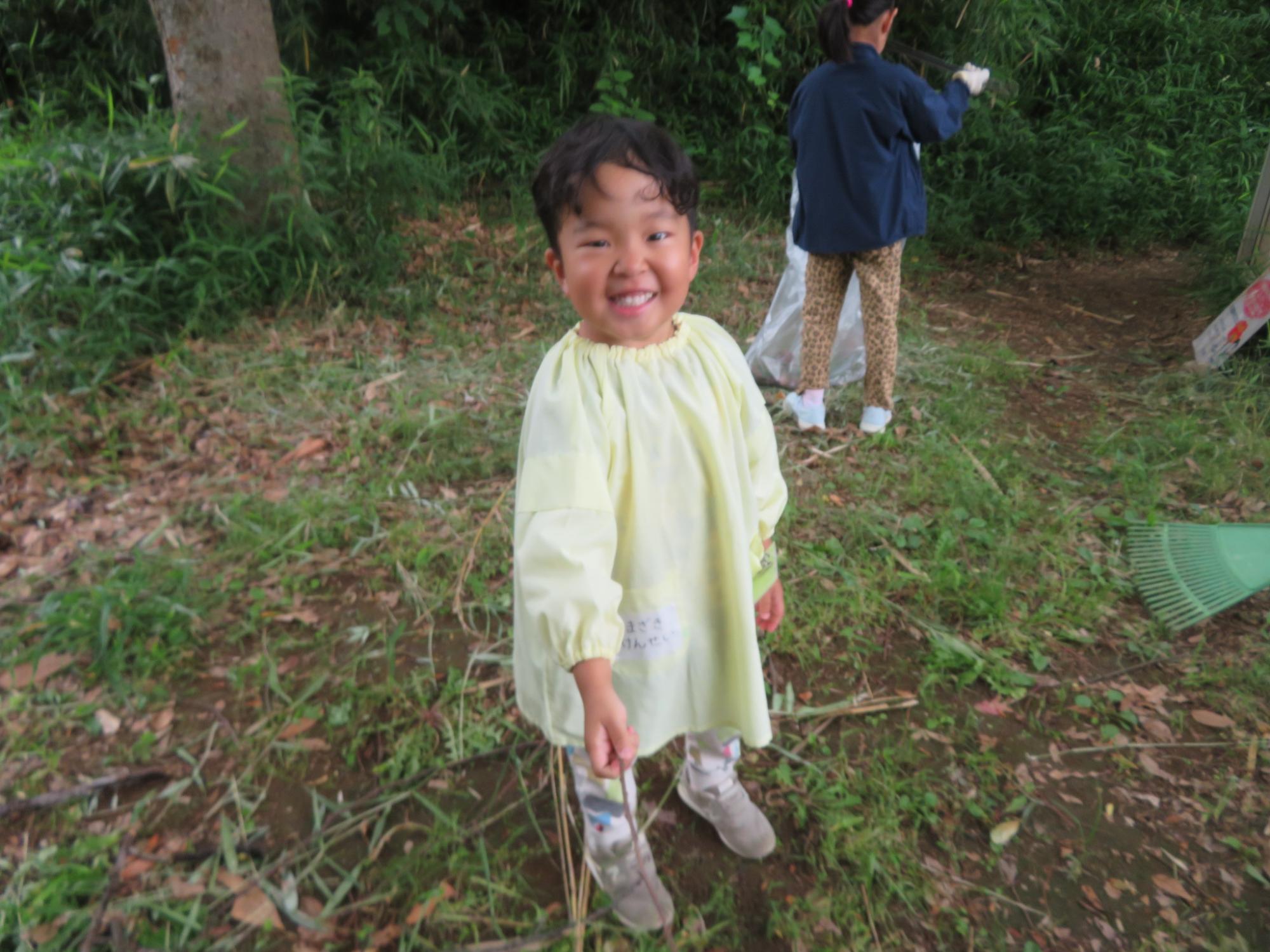 掃除している幼児が笑顔でポーズしている写真