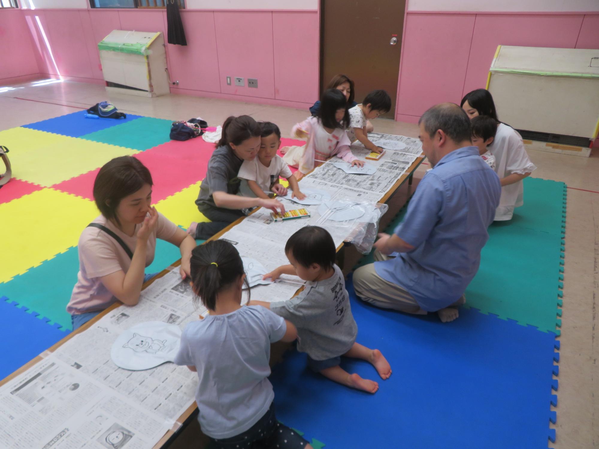 幼児親子が工作用の風船に色を塗っている様子