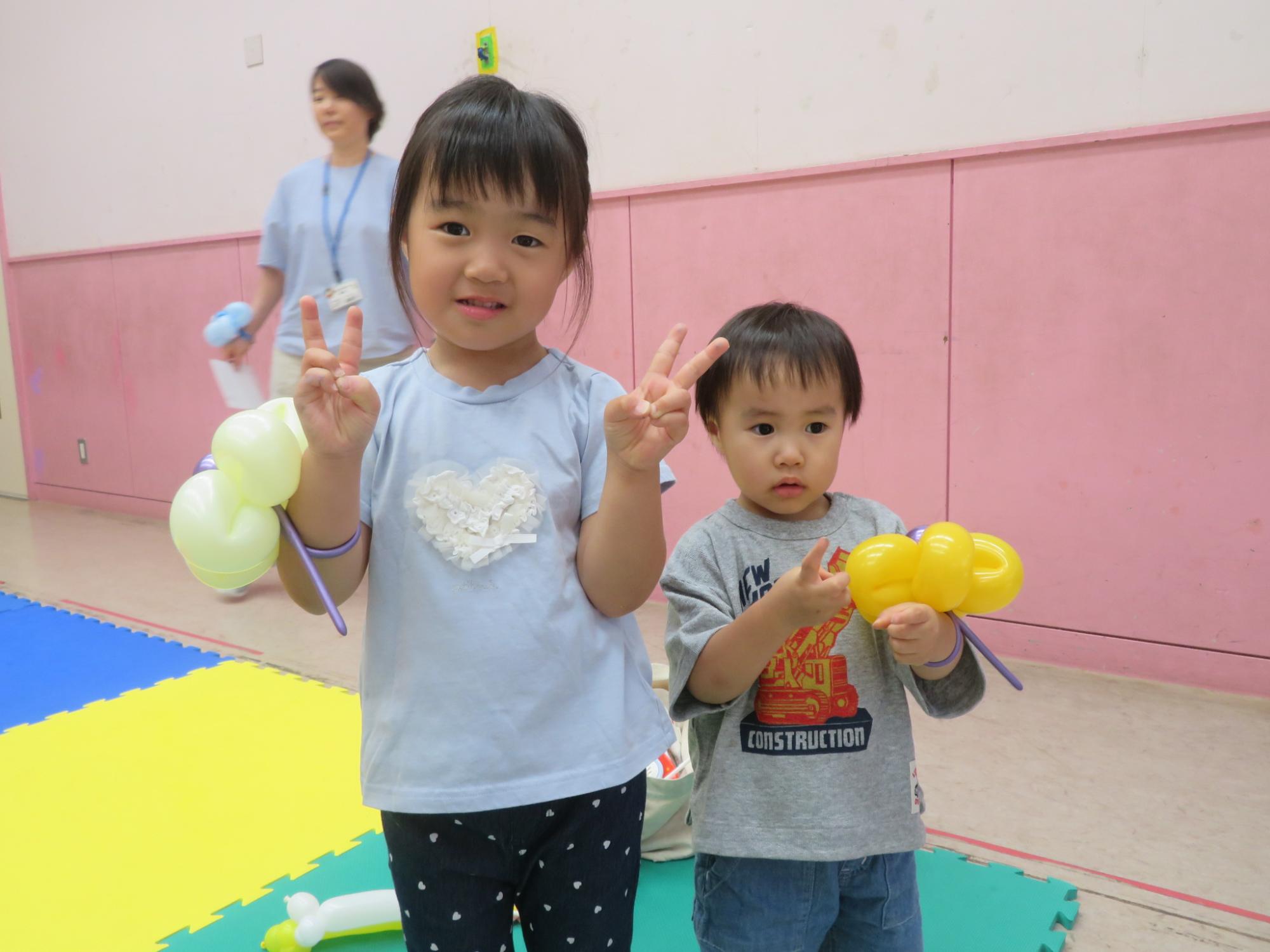 講師にバルーンで作ってもらった花を腕につけて姉弟でポーズしている様子