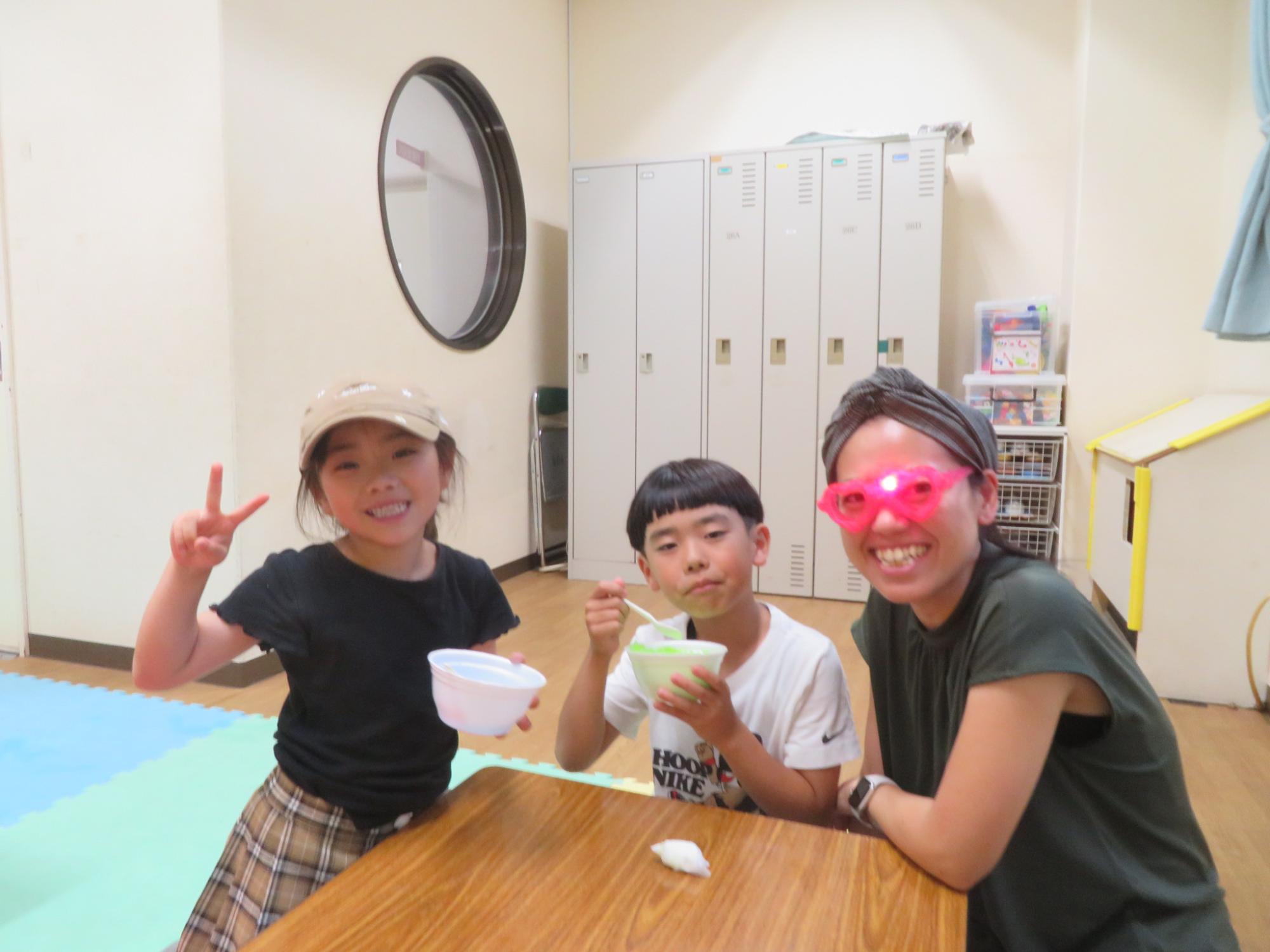 光るメガねをしているお母さんとかき氷をたべる2人のこどもたちの写真