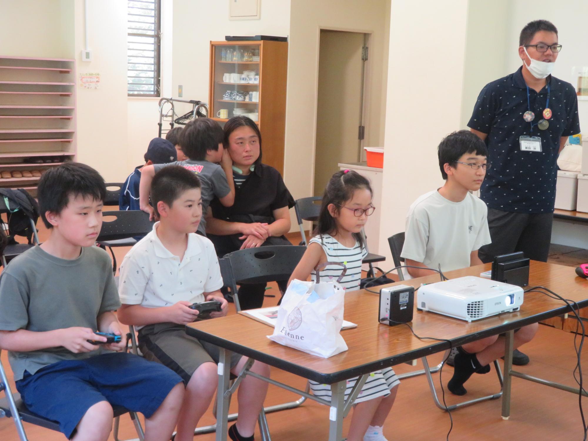 参加者4人が椅子に座り、ゲーム対戦している様子