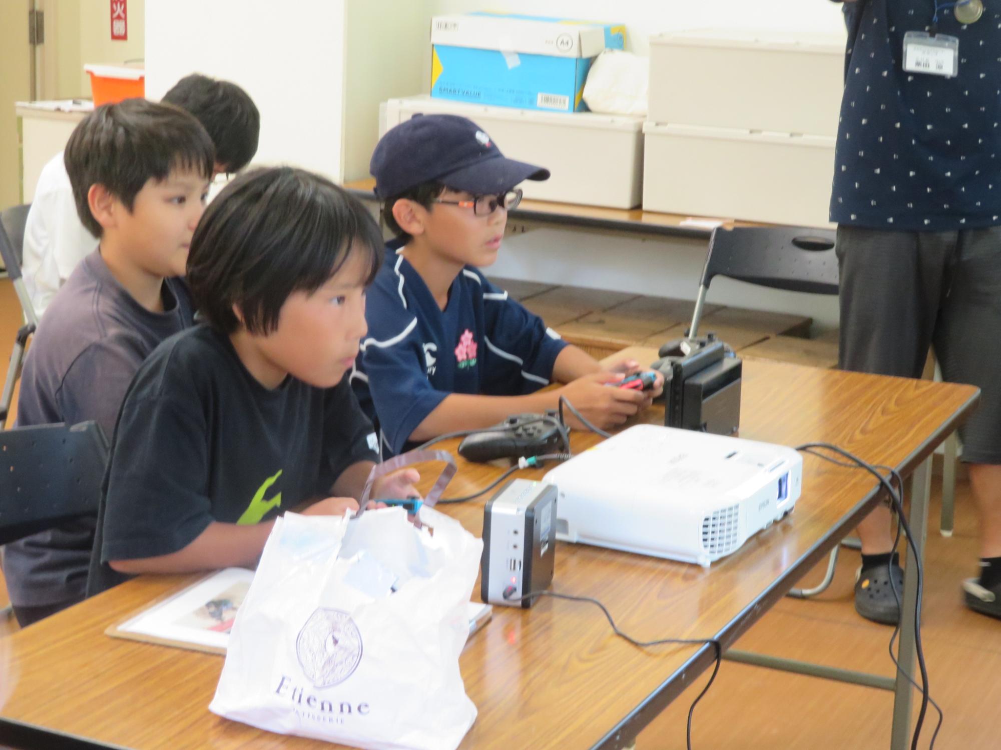 参加者3人が椅子に座り、真剣にゲーム対戦している様子