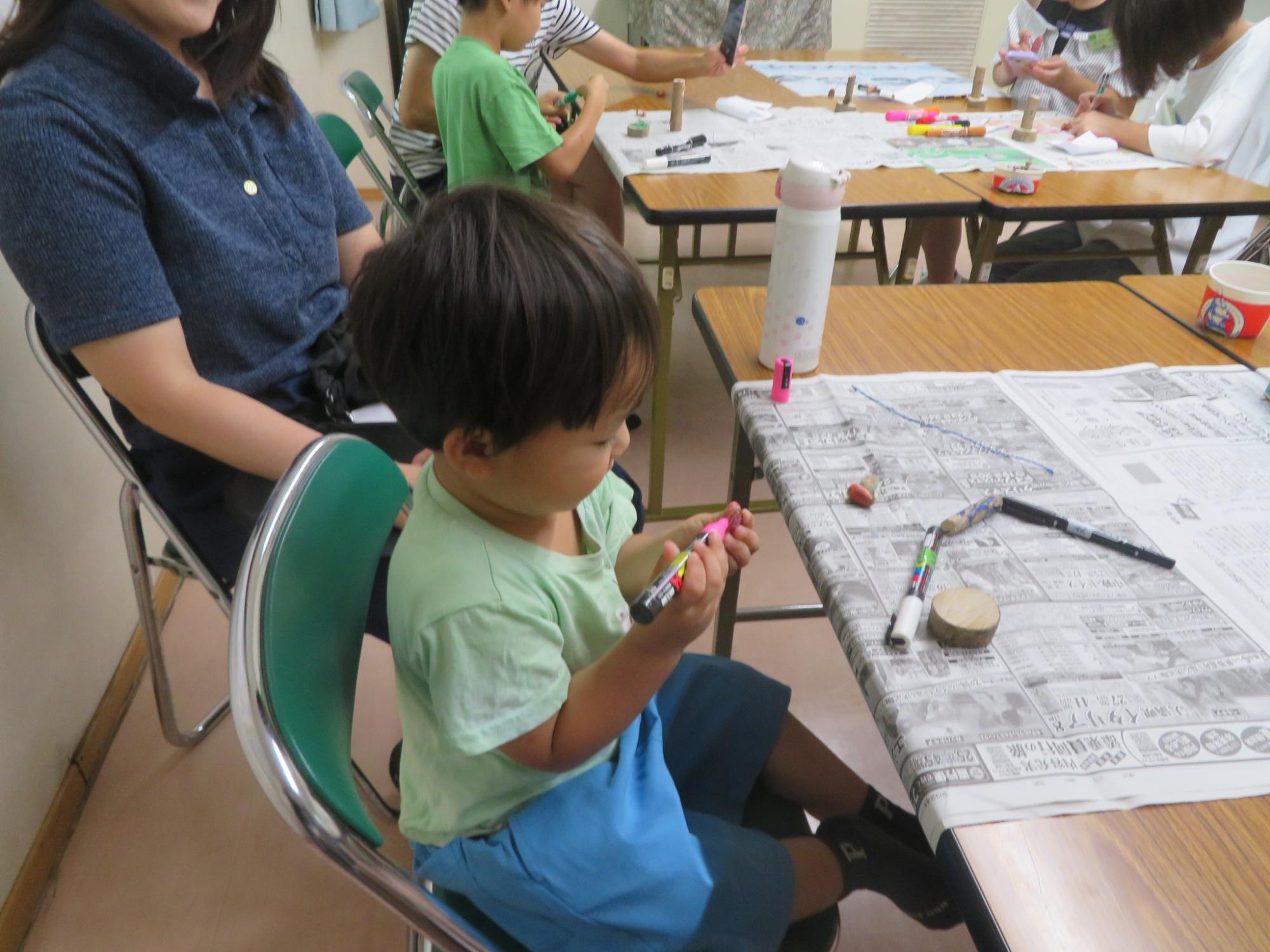 幼児がピンク色のマジックでどんぐりを塗っている様子