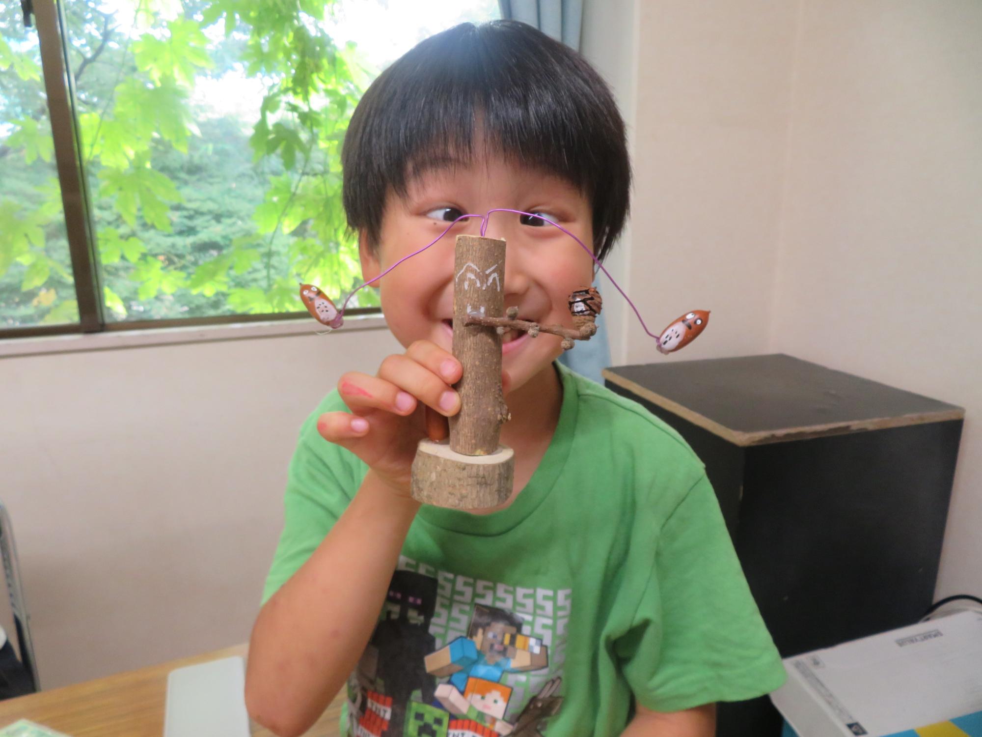 完成したどんぐりやじろべえを見せている男の子の写真