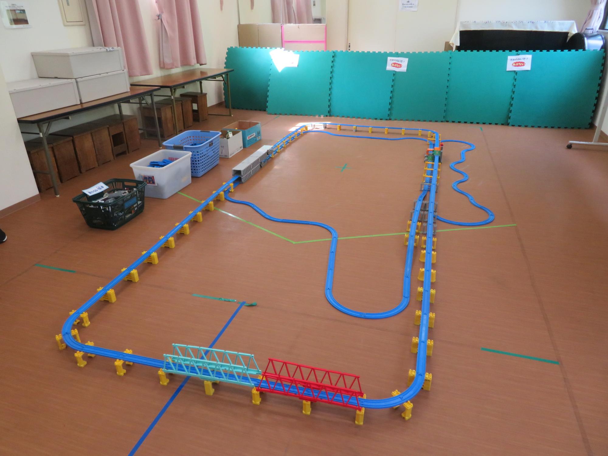 部屋にプラレールのコースが設置されている写真