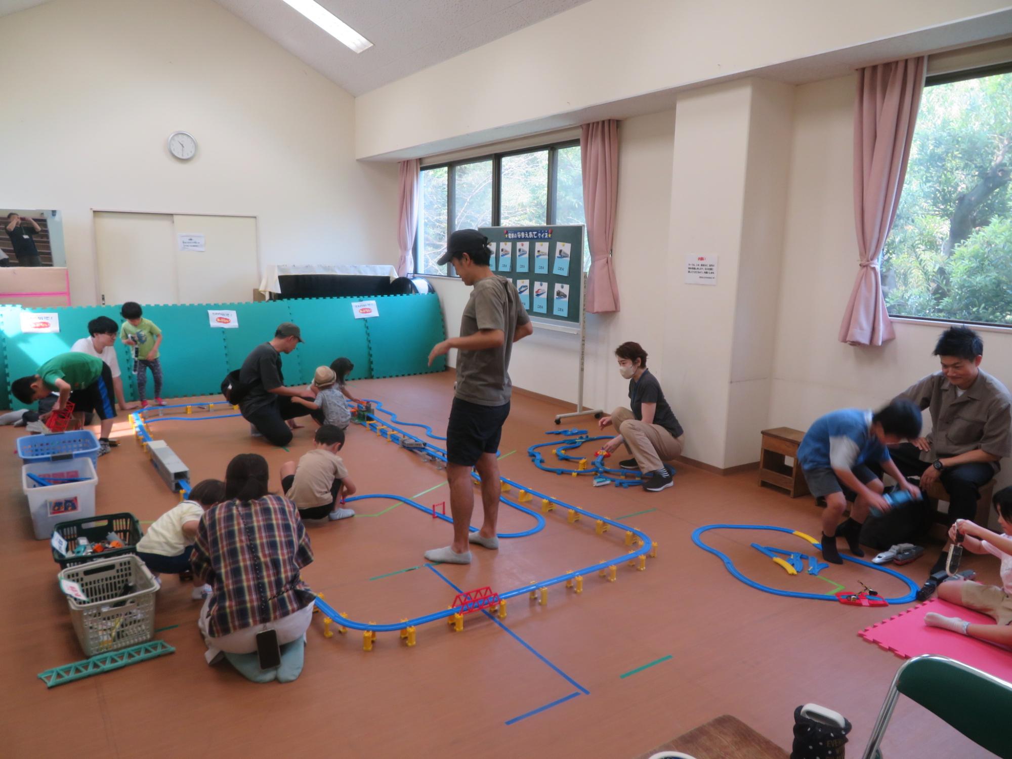 設置されたプラレールのコースを使って幼児親子や小学生が遊んでいる写真