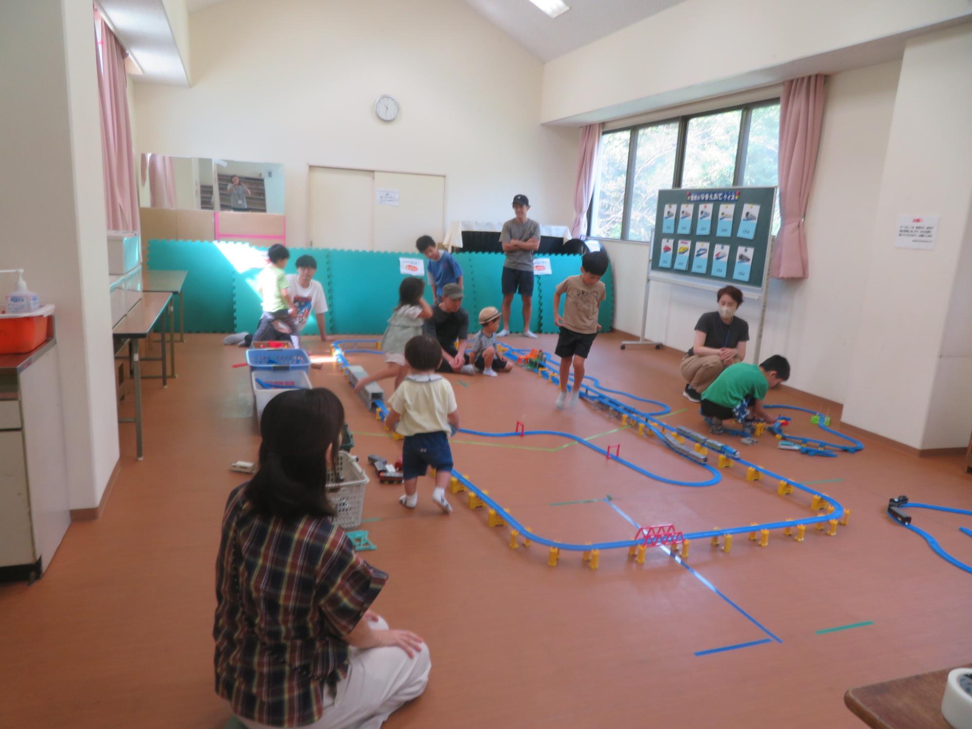 設置されたプラレールのコースを使って幼児親子や小学生が遊んでいる写真