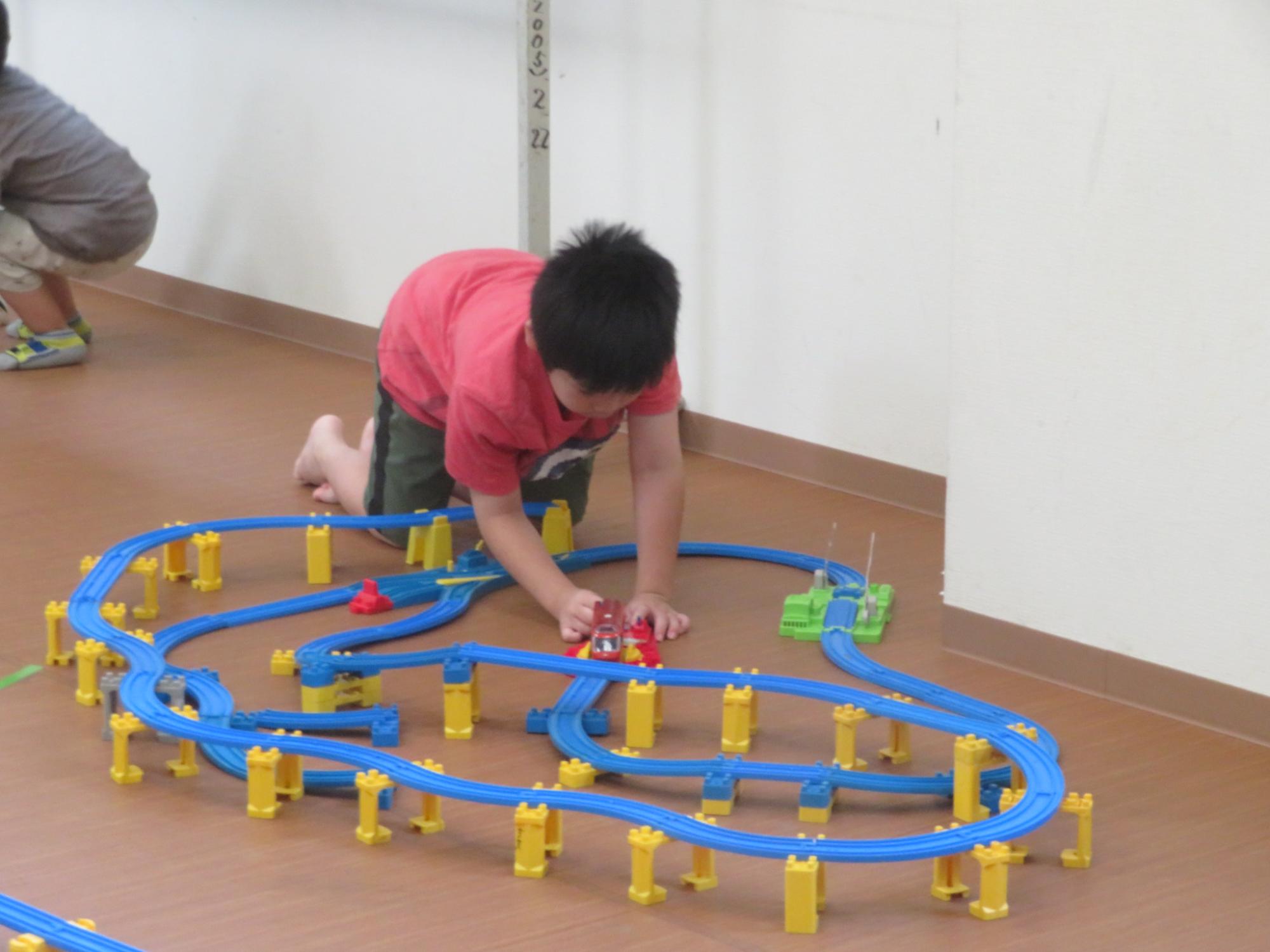 自分で作ったプラレールのコースで電車を走らせて遊んでいる写真