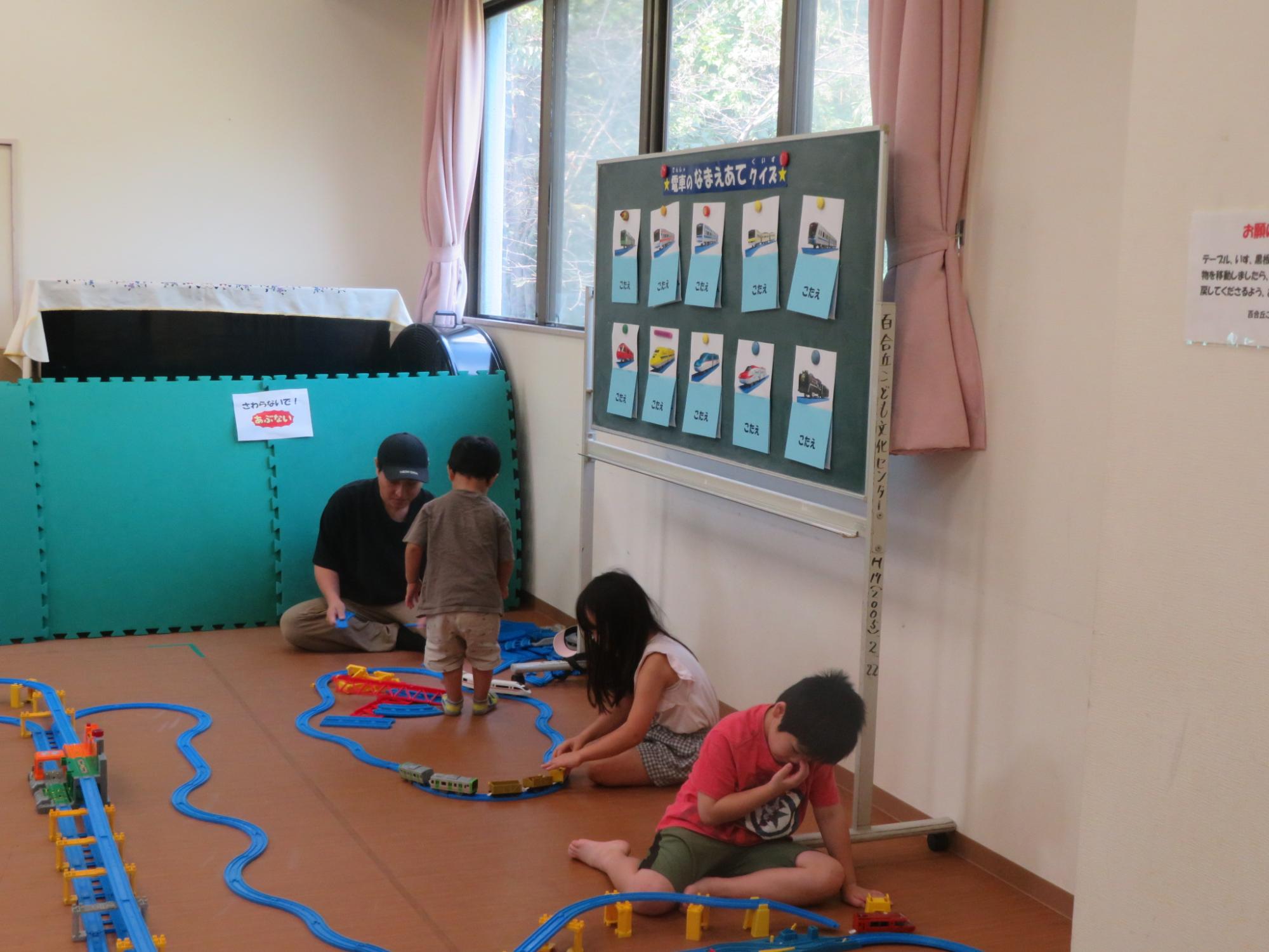 自分で作ったプラレールのコースで電車を走らせて遊んでいる写真