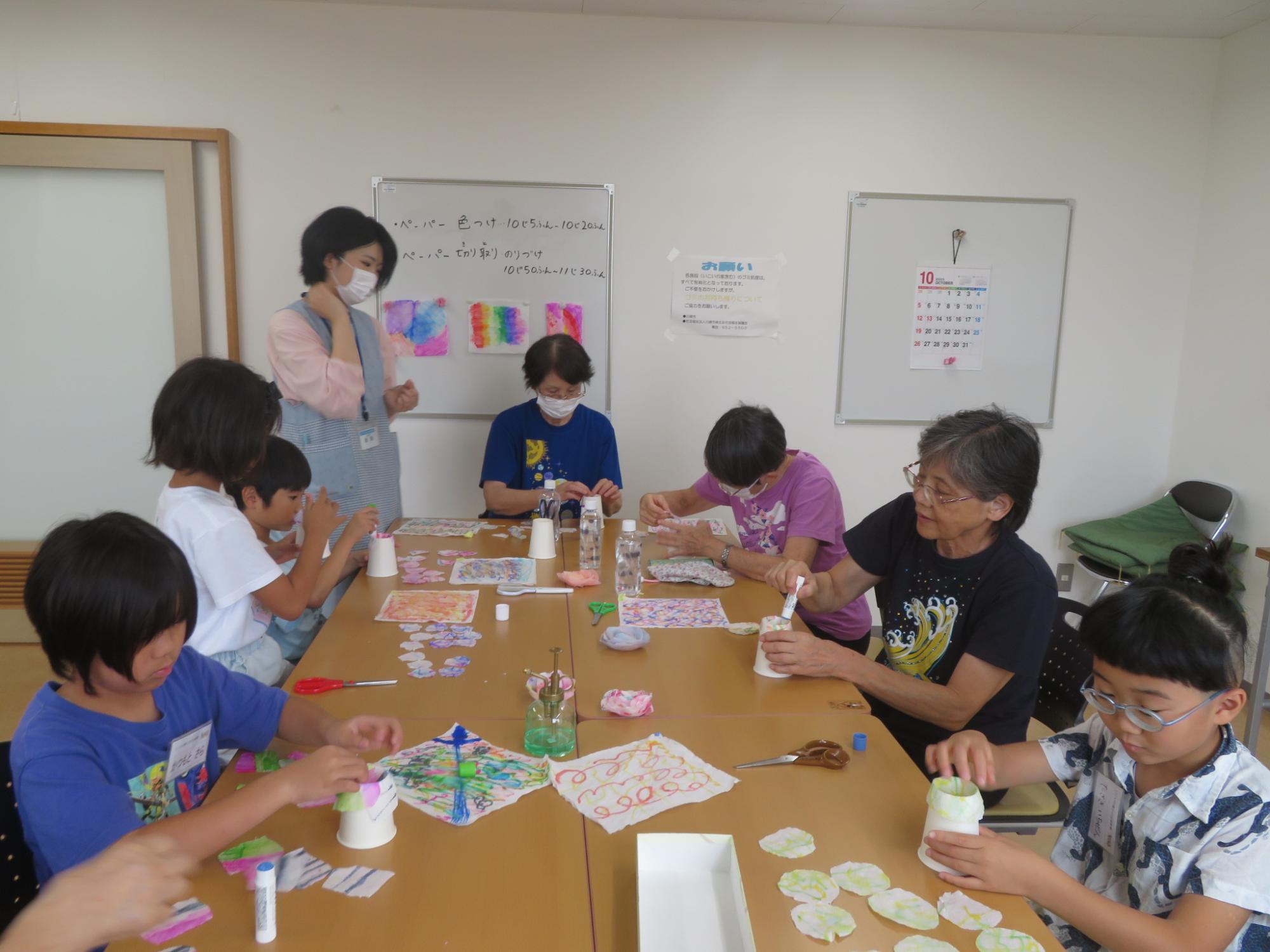乾いた材料を丸く切り抜き、紙コップで花を作っている男の子