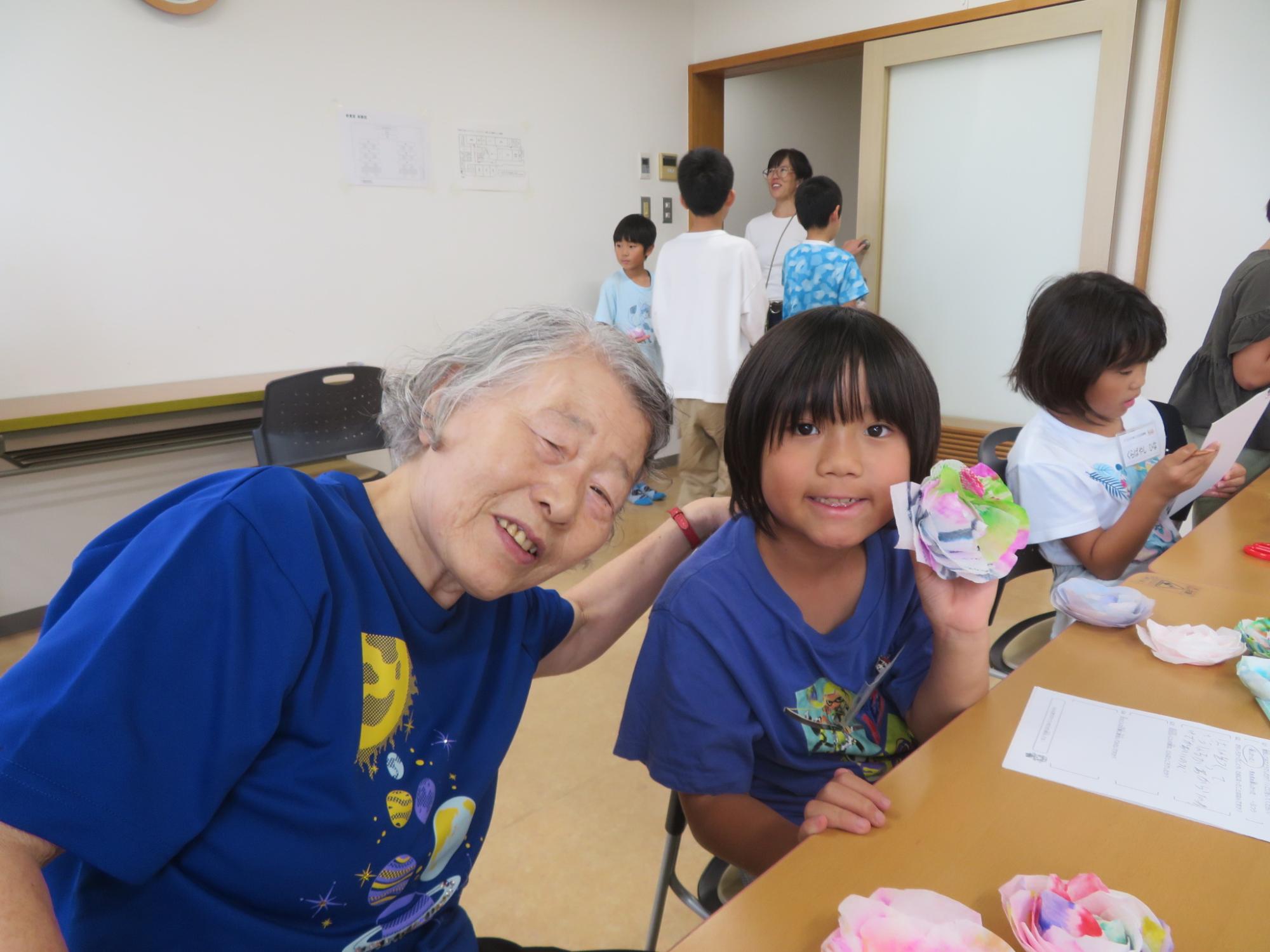 いこいの家の人と作品を持った児童の写真