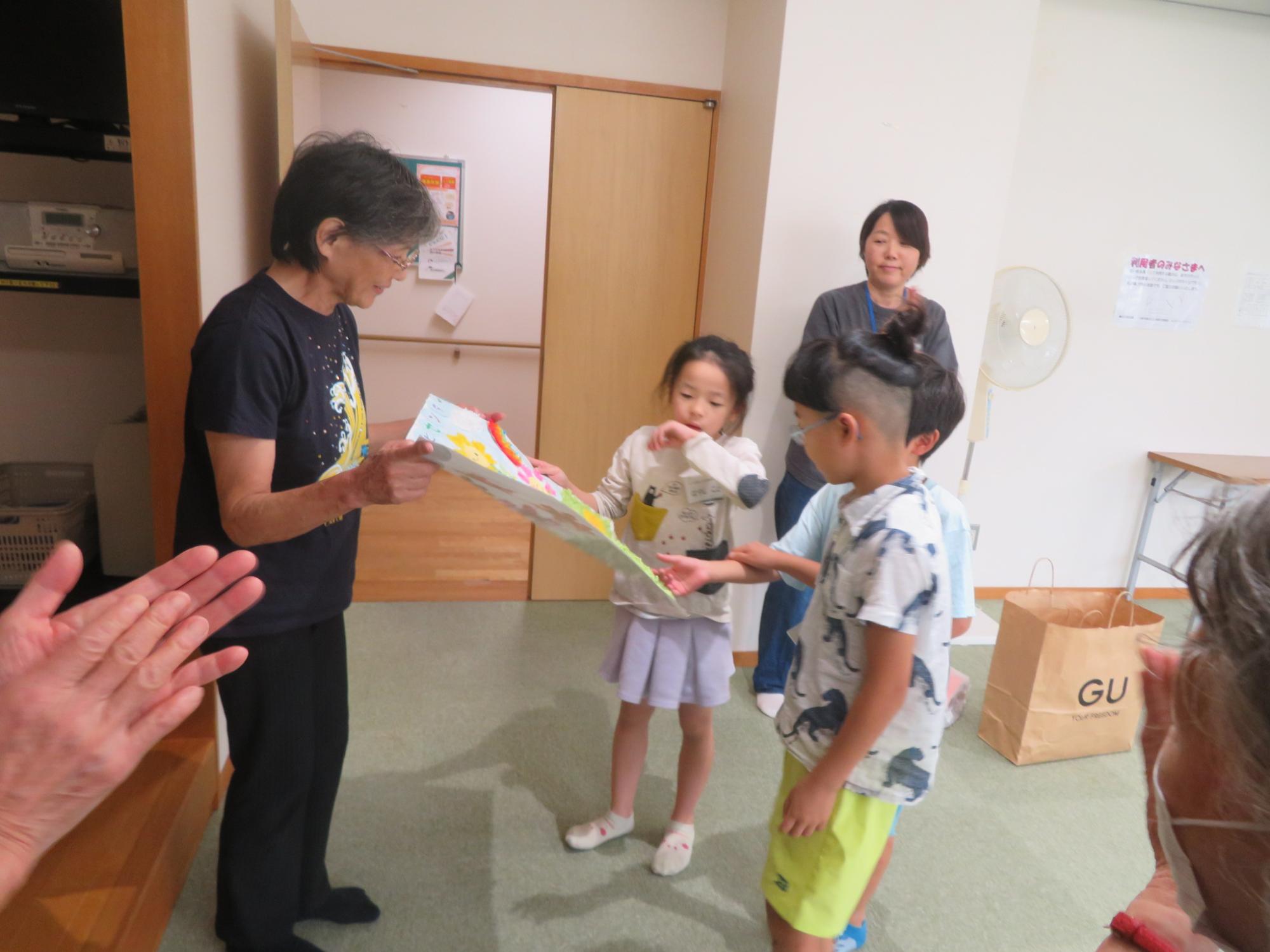 児童たちが、いこいの家の方たちにプレゼントしている写真