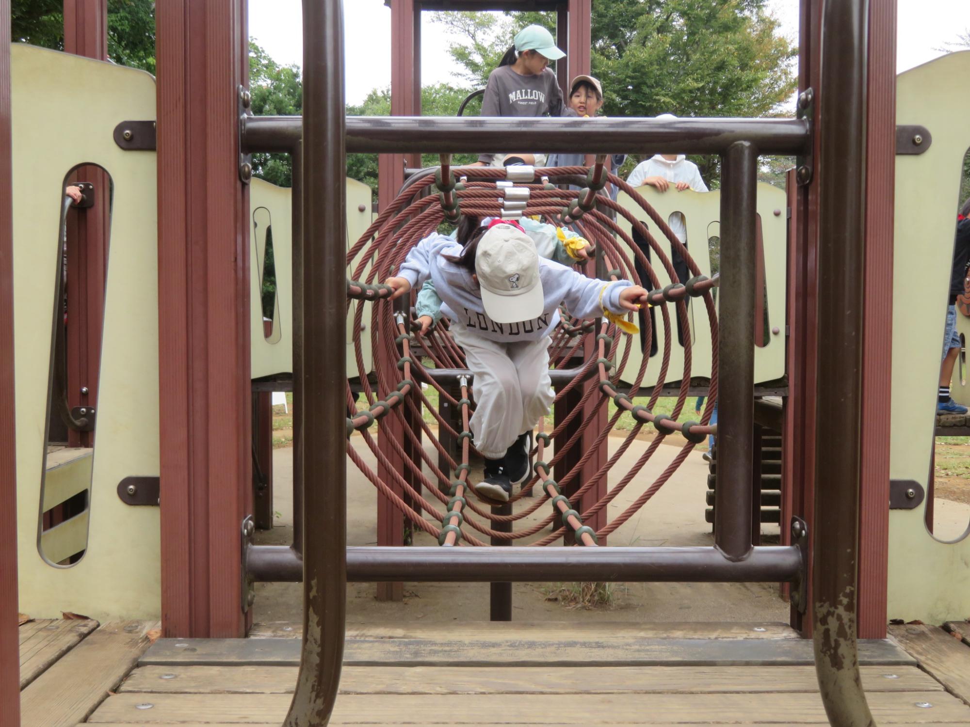 遊具でアスレチックを楽しんでいる児童の写真