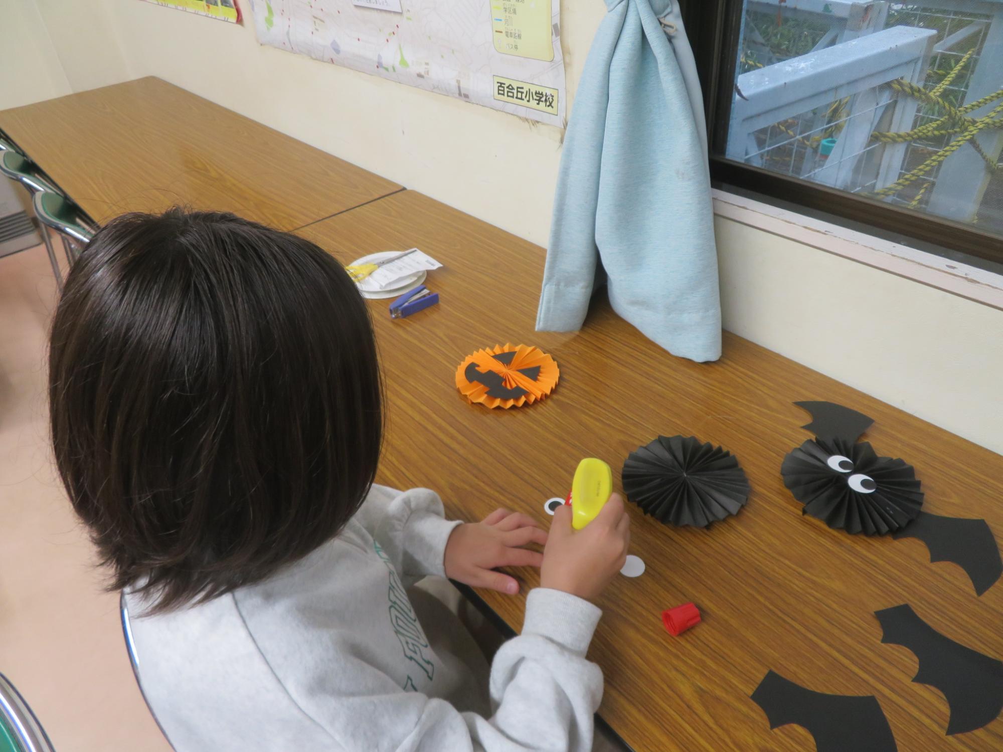 ペーパーファンでコウモリやカボチャを作っている女の子の写真