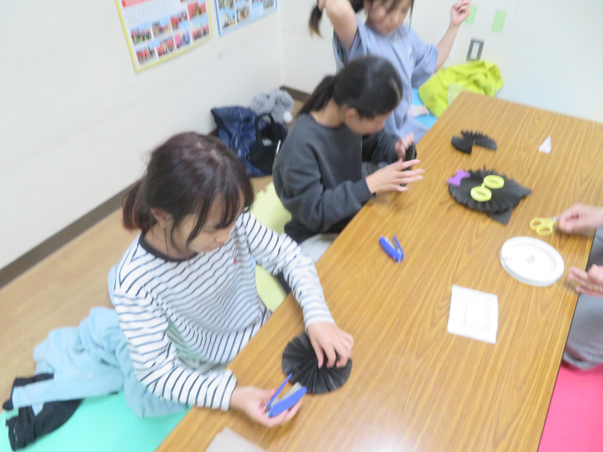 ペーパーファンで黒ネコを作っている女の子たちの写真