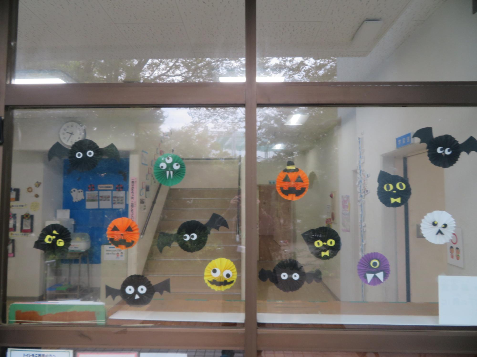 玄関横の窓にペーパーファンを装飾している様子