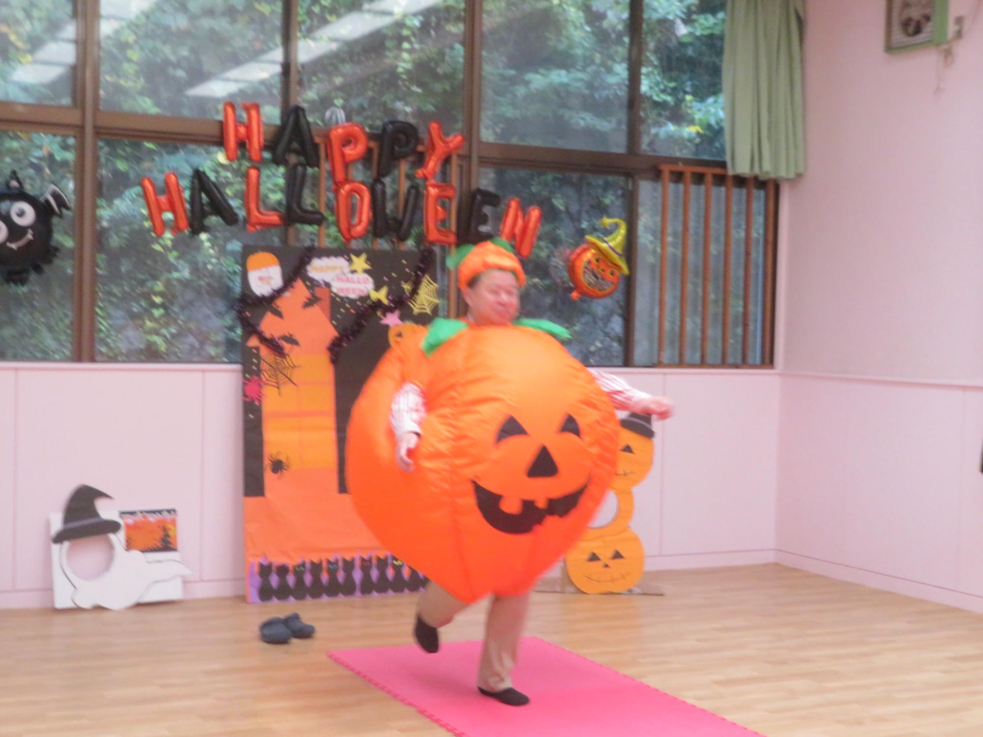 スタッフが大きなカボチャの仮装をしてランウェイを歩いている写真