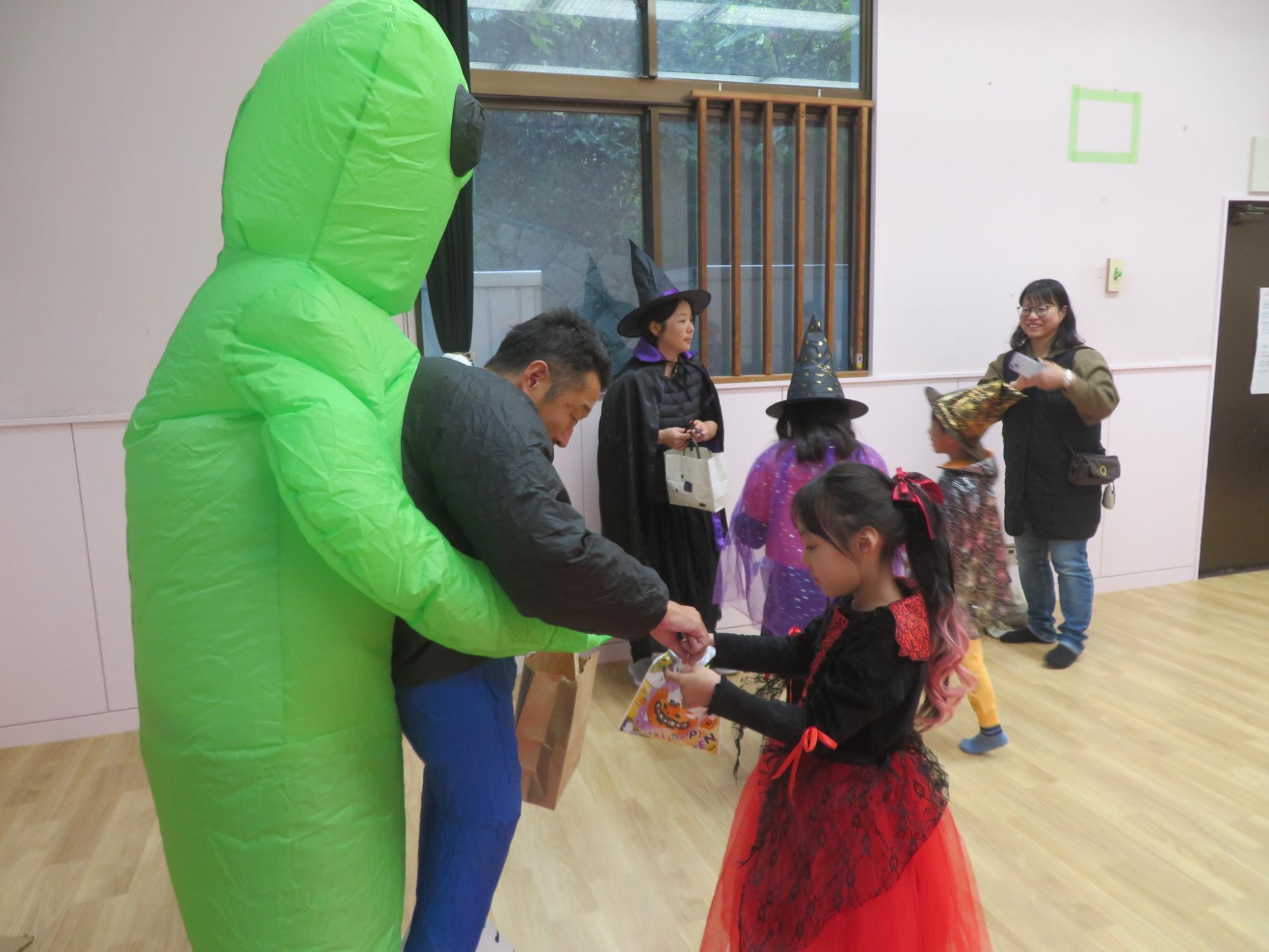 宇宙人に仮装した館長が子どもたちにお菓子を配っている写真