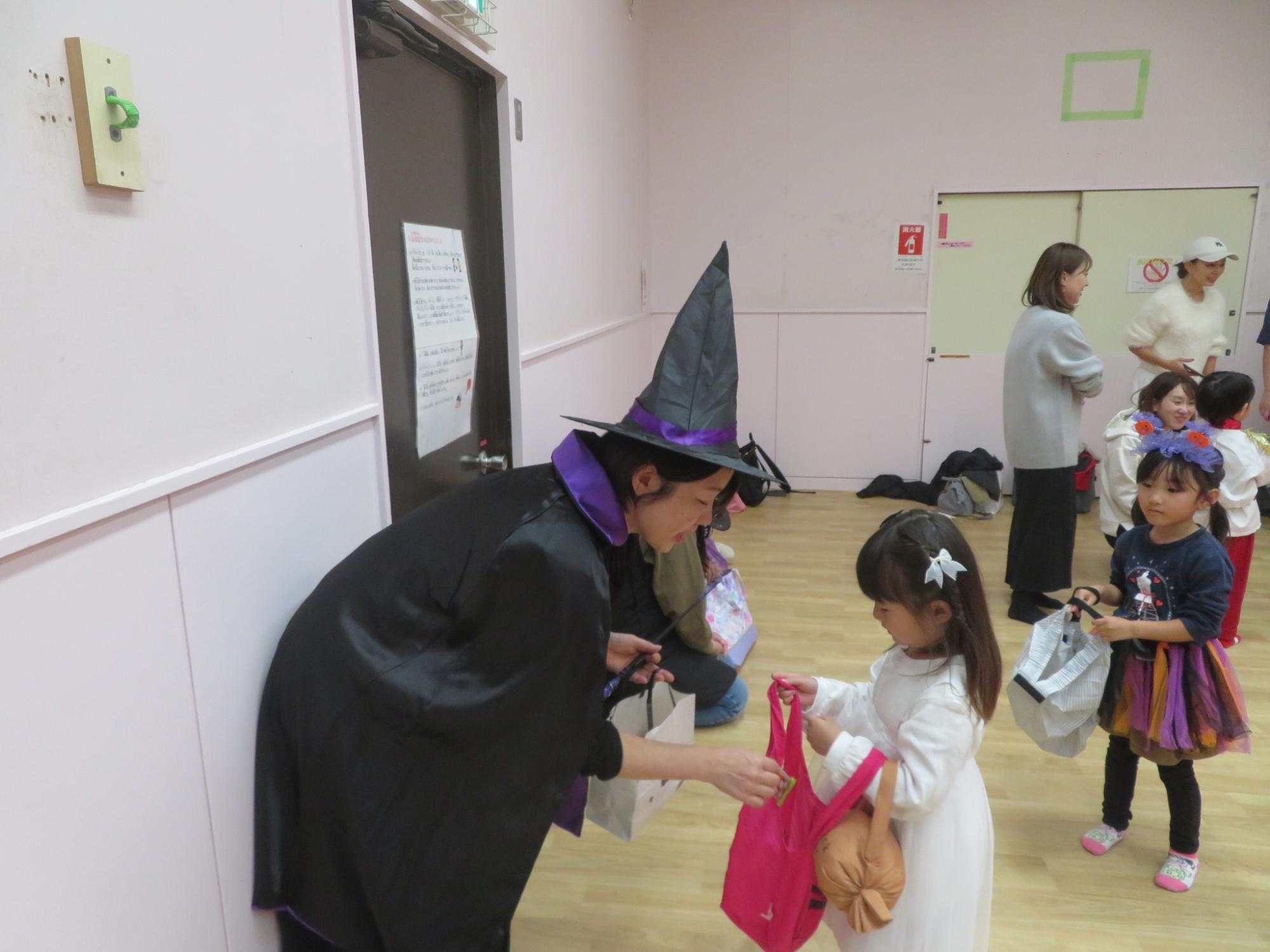 魔法使いに仮装したスタッフが子どもたちにお菓子を配っている写真