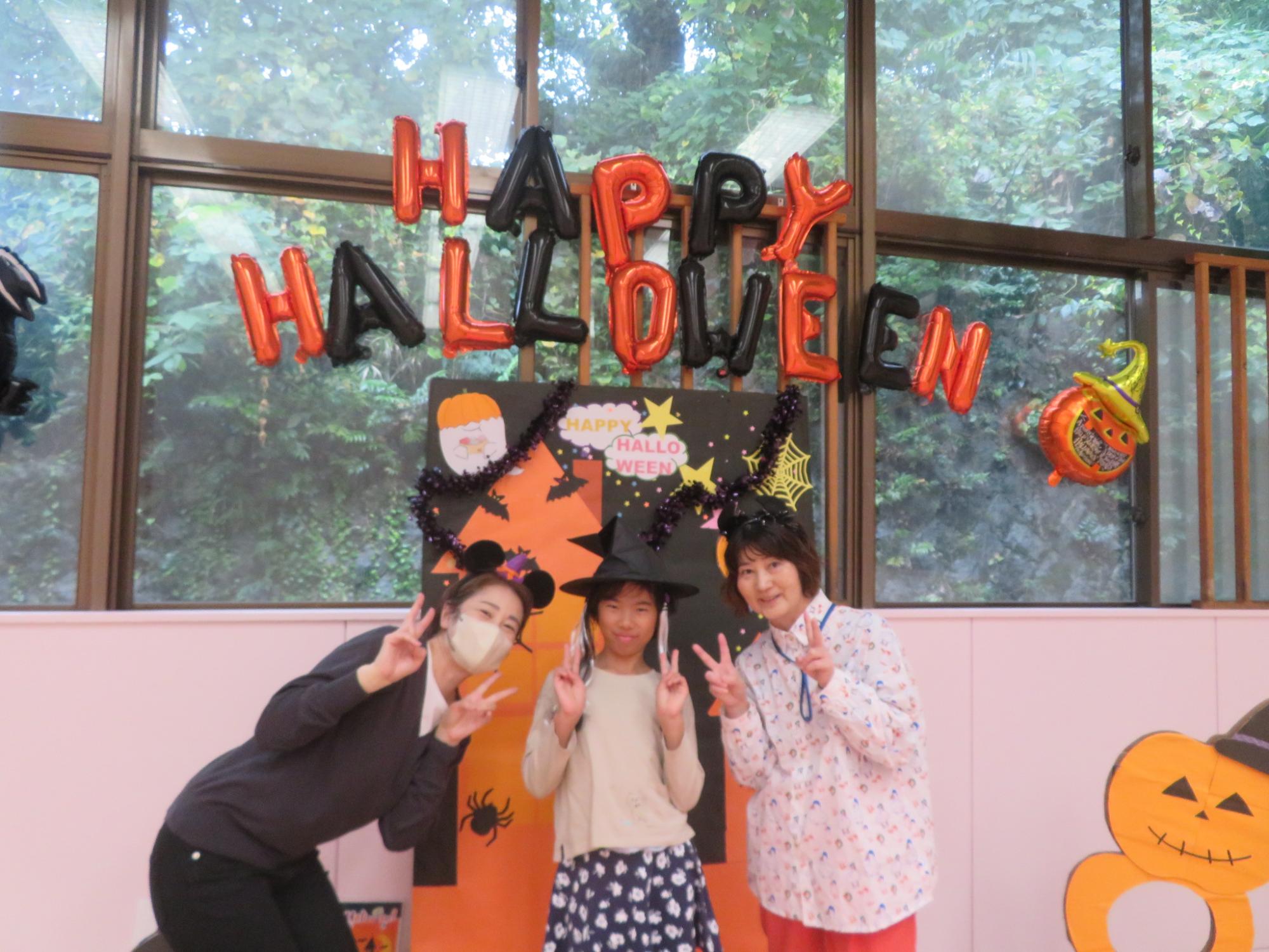ハロウィンの装飾をバックにスタッフとポースしている写真