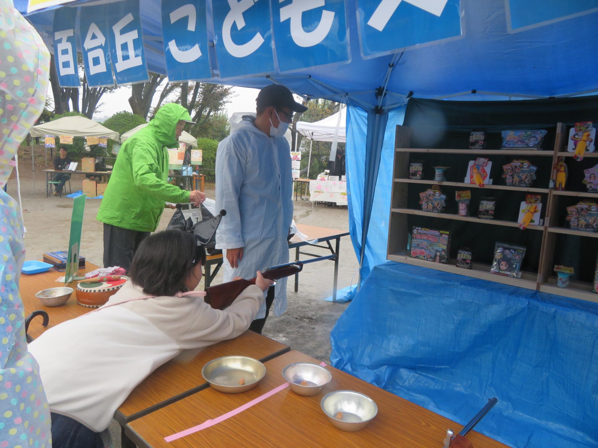 射的の銃をもって景品をねらう児童の写真