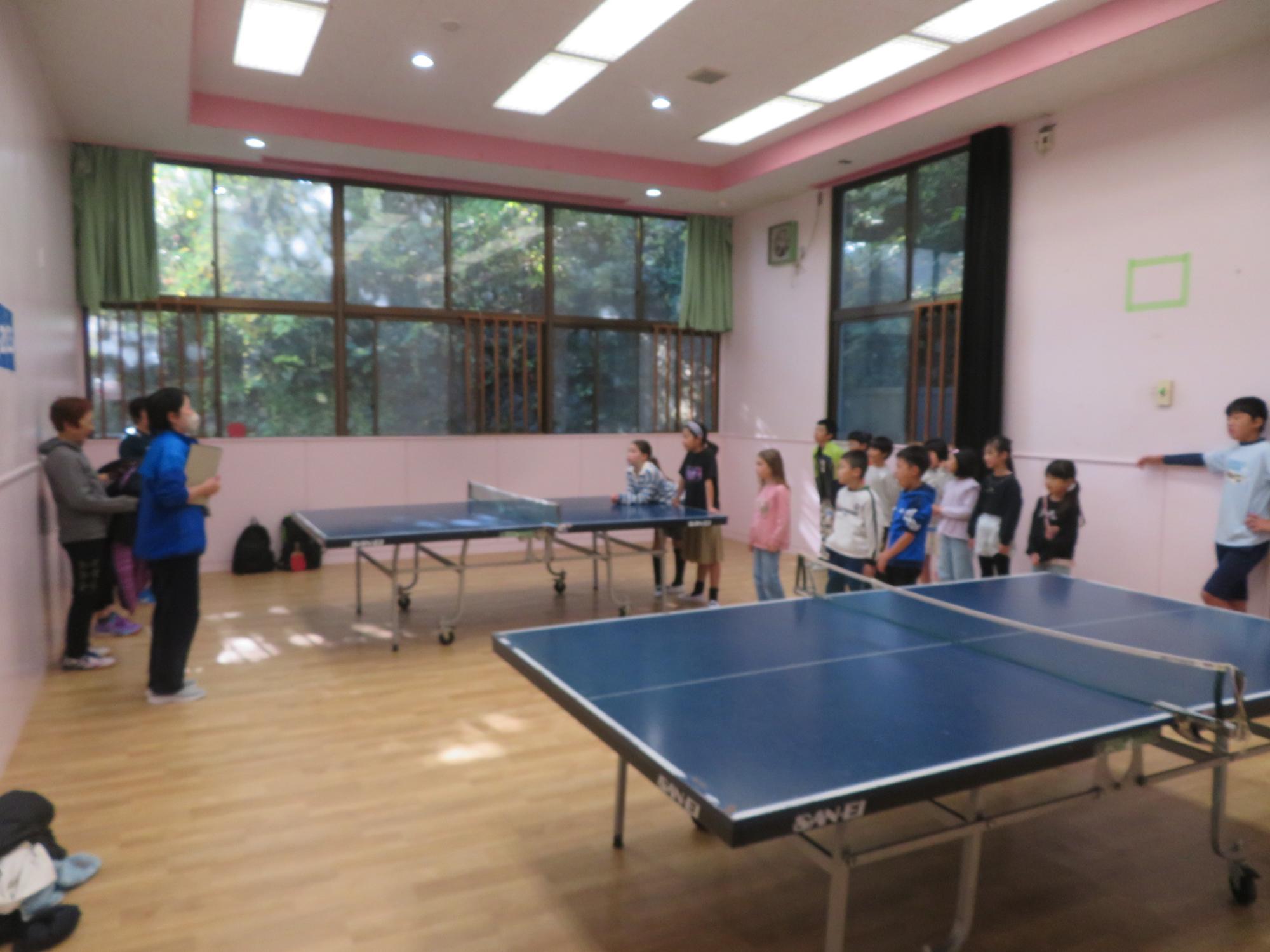 卓球交流会開始前の挨拶をしている職員と子どもたちの写真
