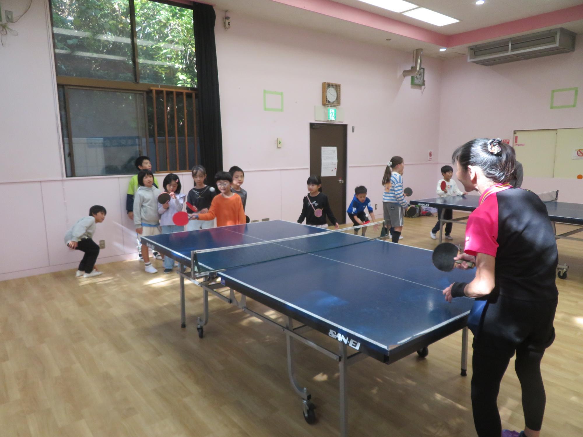 講師の方に教えてもらいながら卓球の打ち合いをしているこどもの写真
