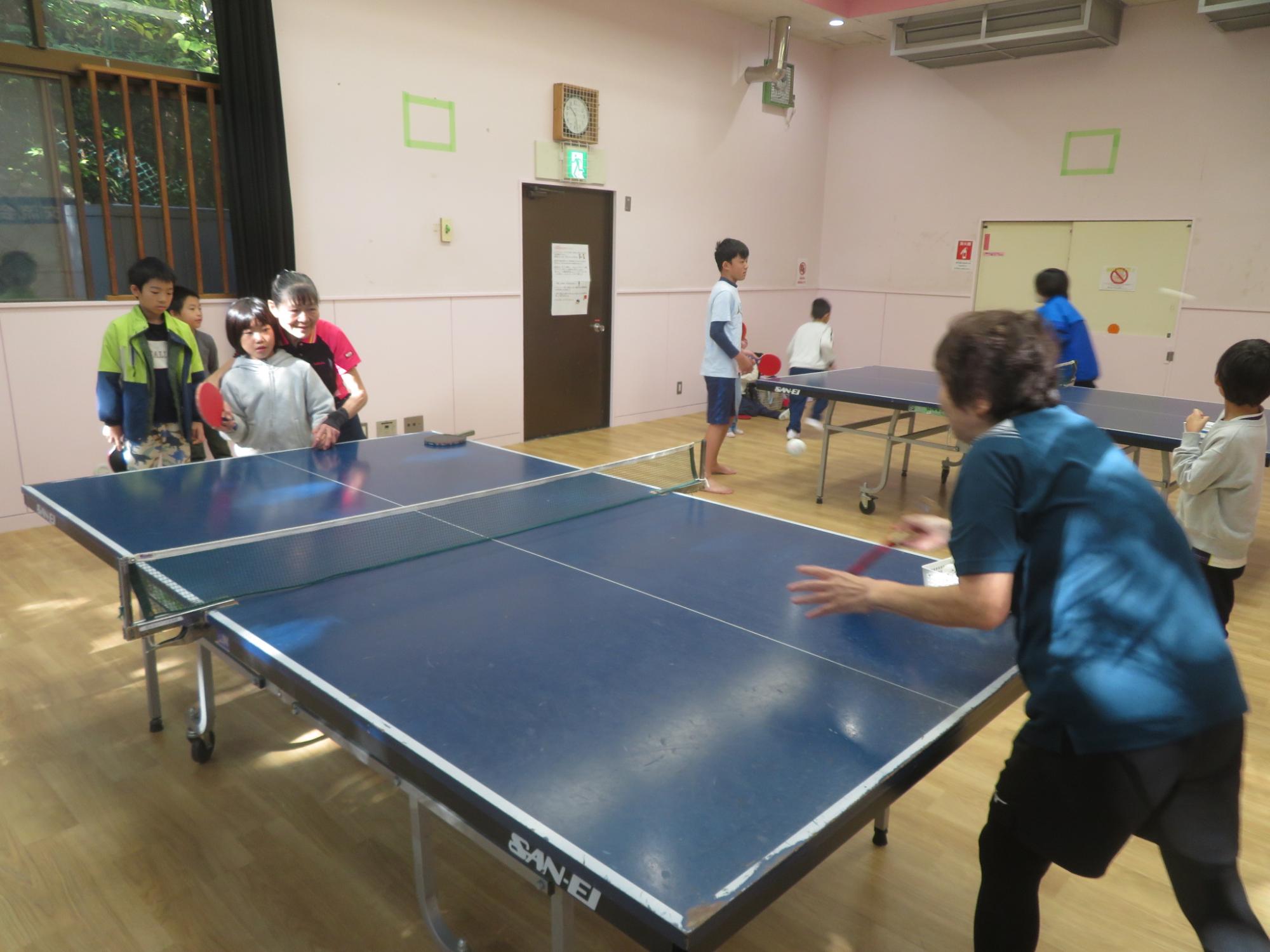 講師の方に教えてもらいながら卓球の打ち合いをしているこどもの写真