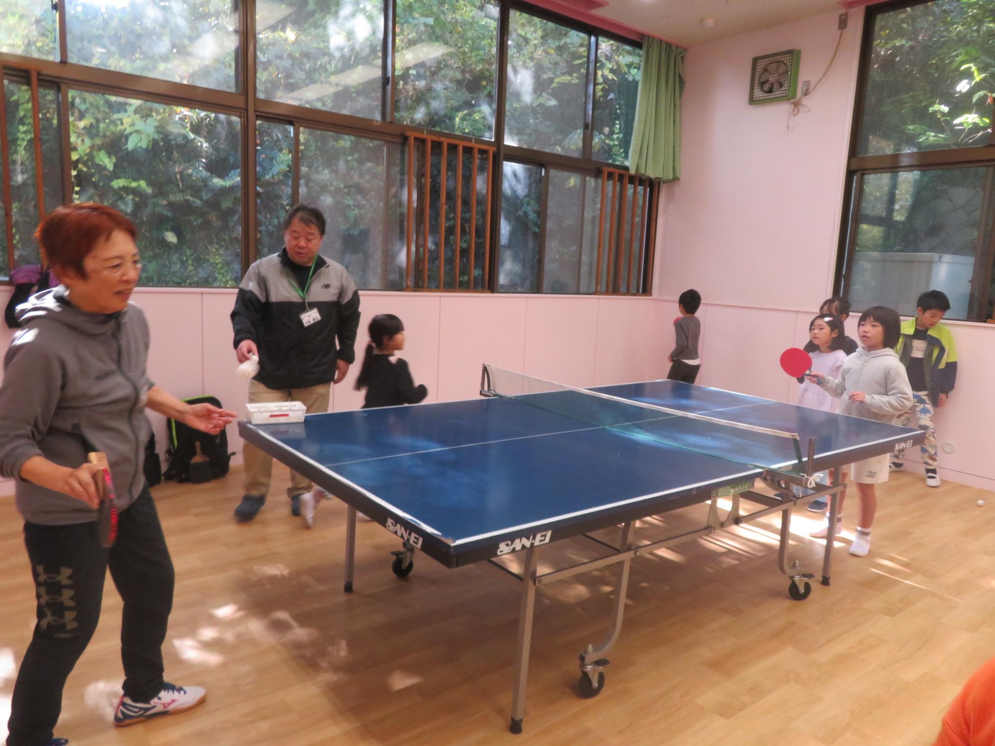 講師の方に教えてもらいながら卓球の打ち合いをしているこどもの写真