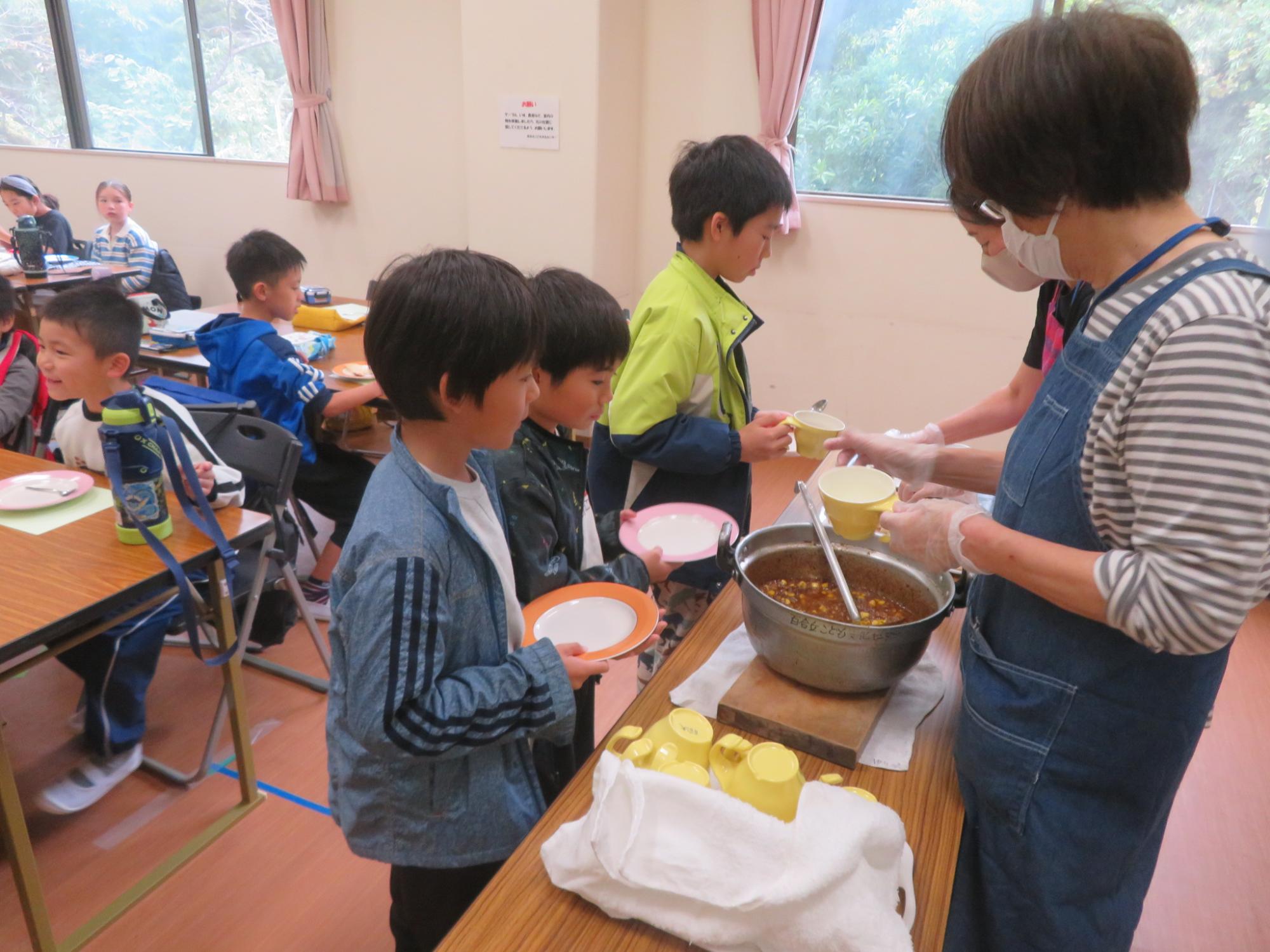 子どもたちがキーマカレーを配膳してもらっている写真