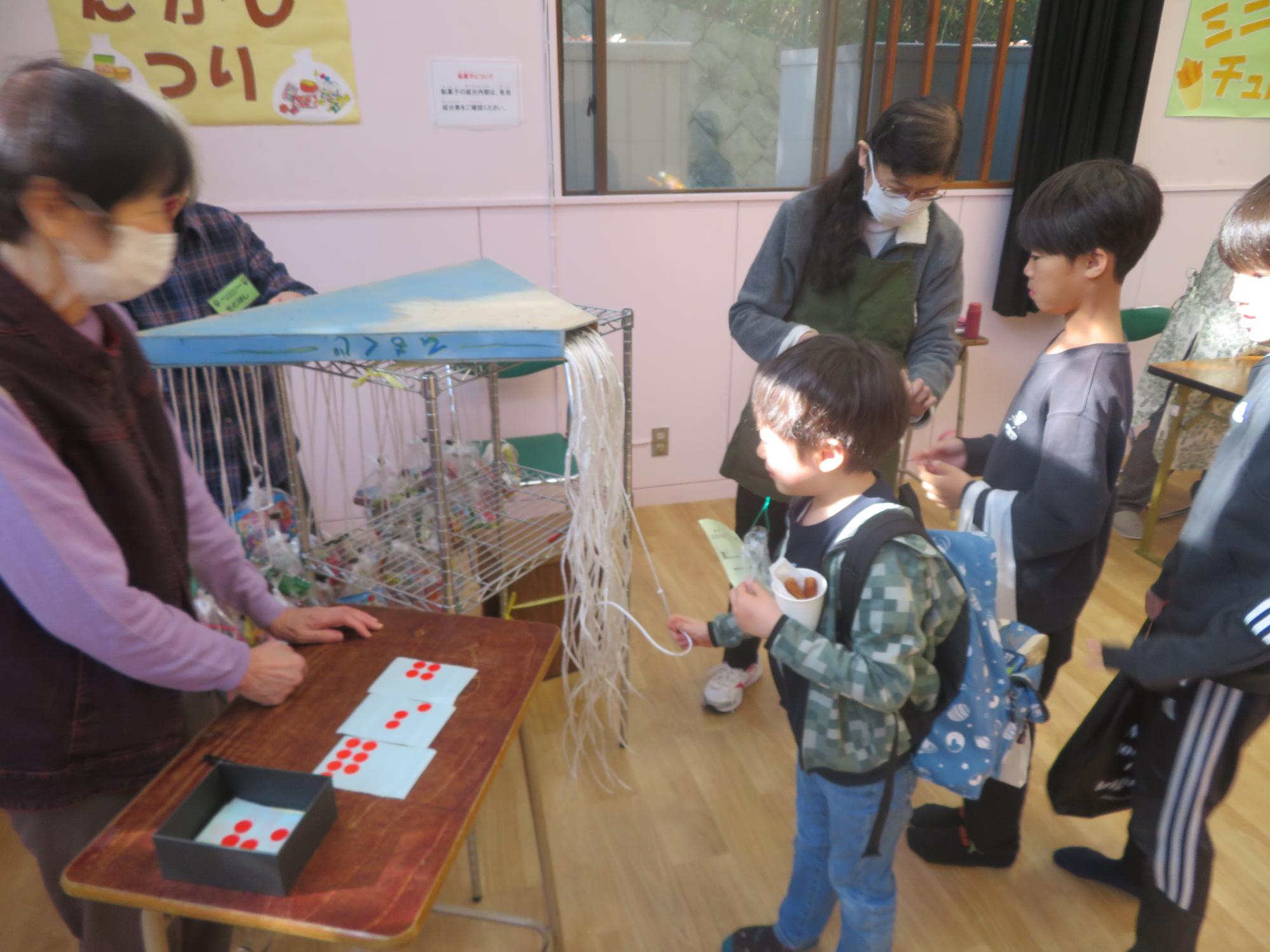 駄菓子釣りコーナーでこどもがひもくじをひいている写真