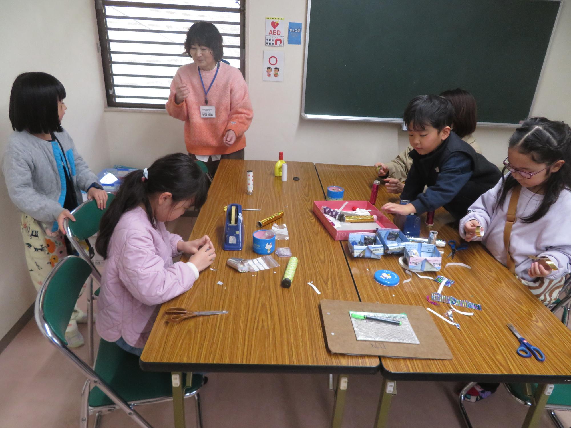 万華鏡工作をしてる小学生と幼児親子の写真